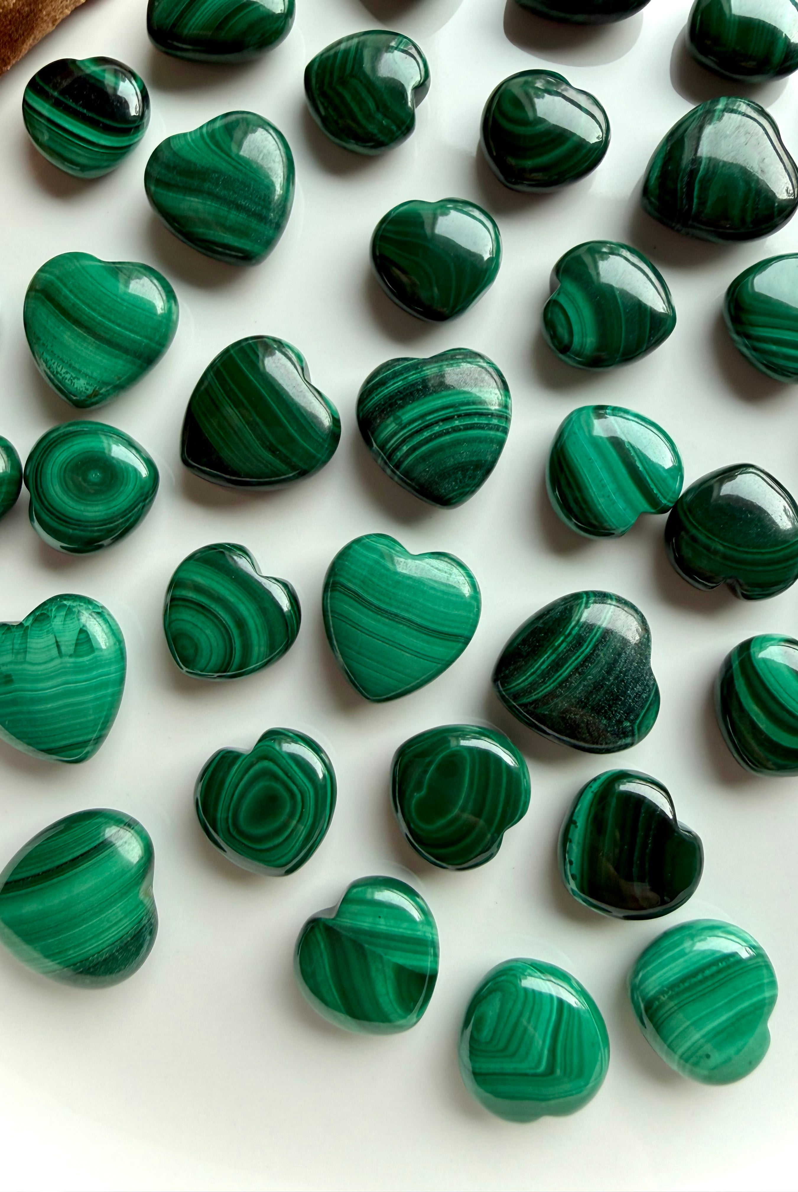 Close-up of polished Malachite heart carvings showing rich banded patterns in vibrant green tones.