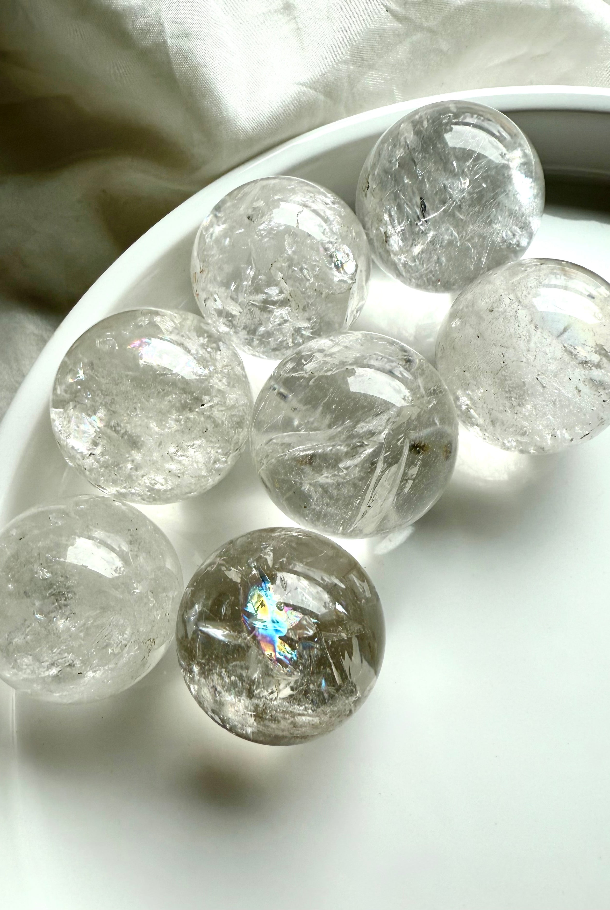 Mini Rainbow Quartz crystal spheres with bright inclusions and clarity in a white dish – healing crystals for energy work and chakra balancing