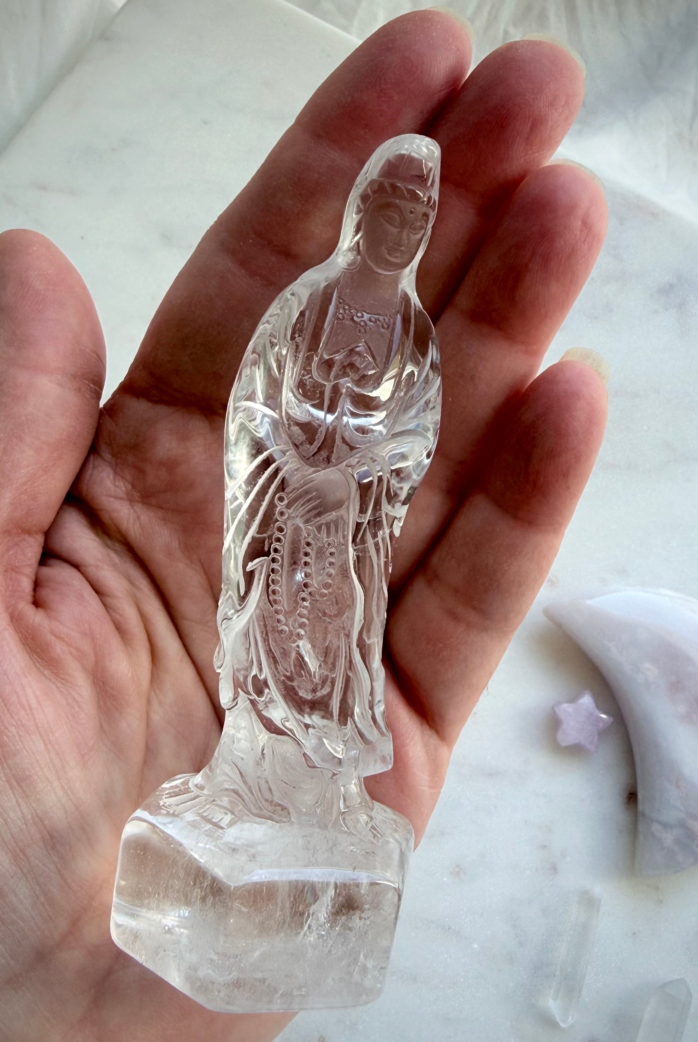 Clear Quartz Quan Yin statue held in the hand showing beautiful clarity and detailed craftsmanship
