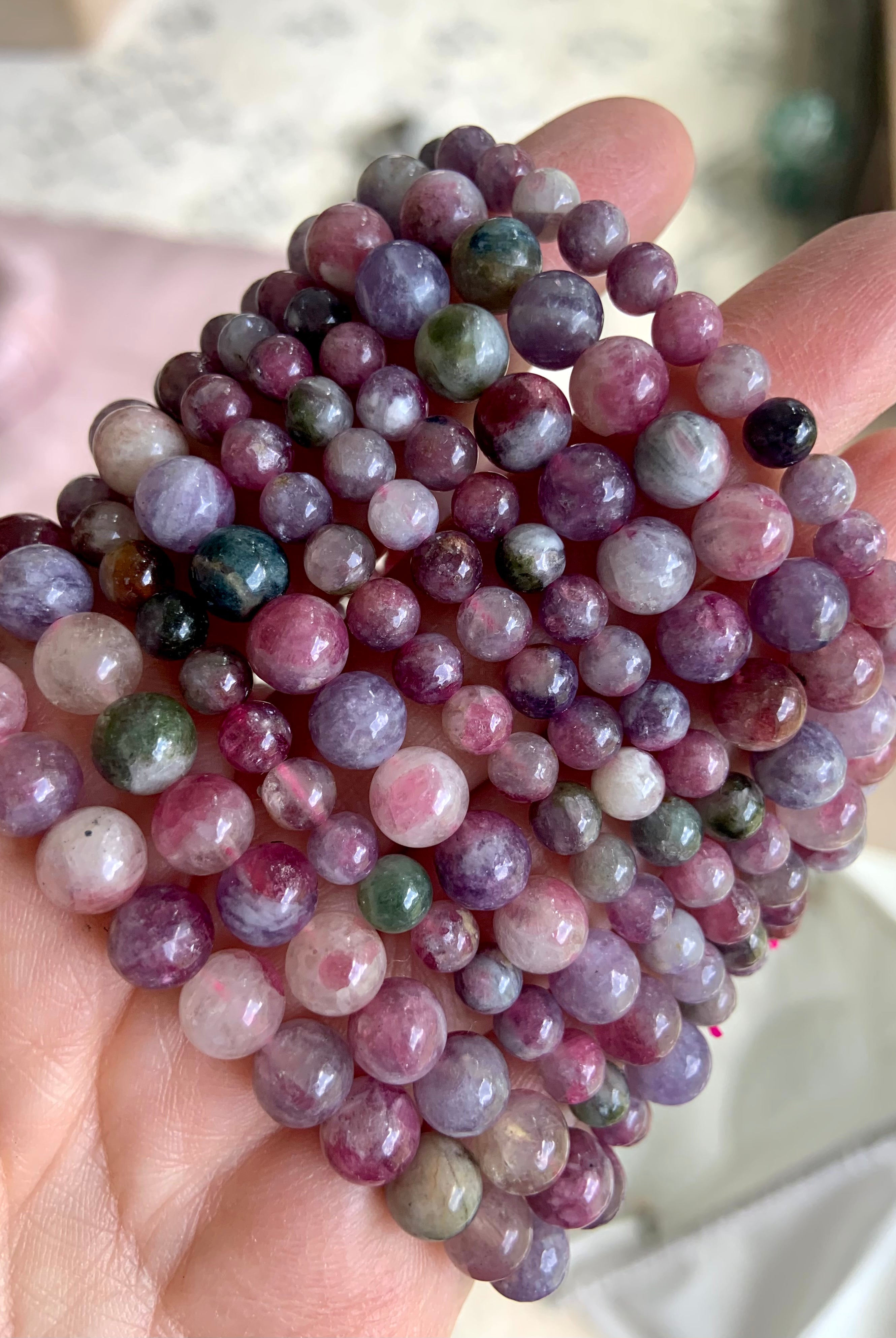 Closeup of stacked Watermelon Tourmaline and Lepidolite bracelets — vibrant crystal beads in mixed sizes for emotional balance + stress relief