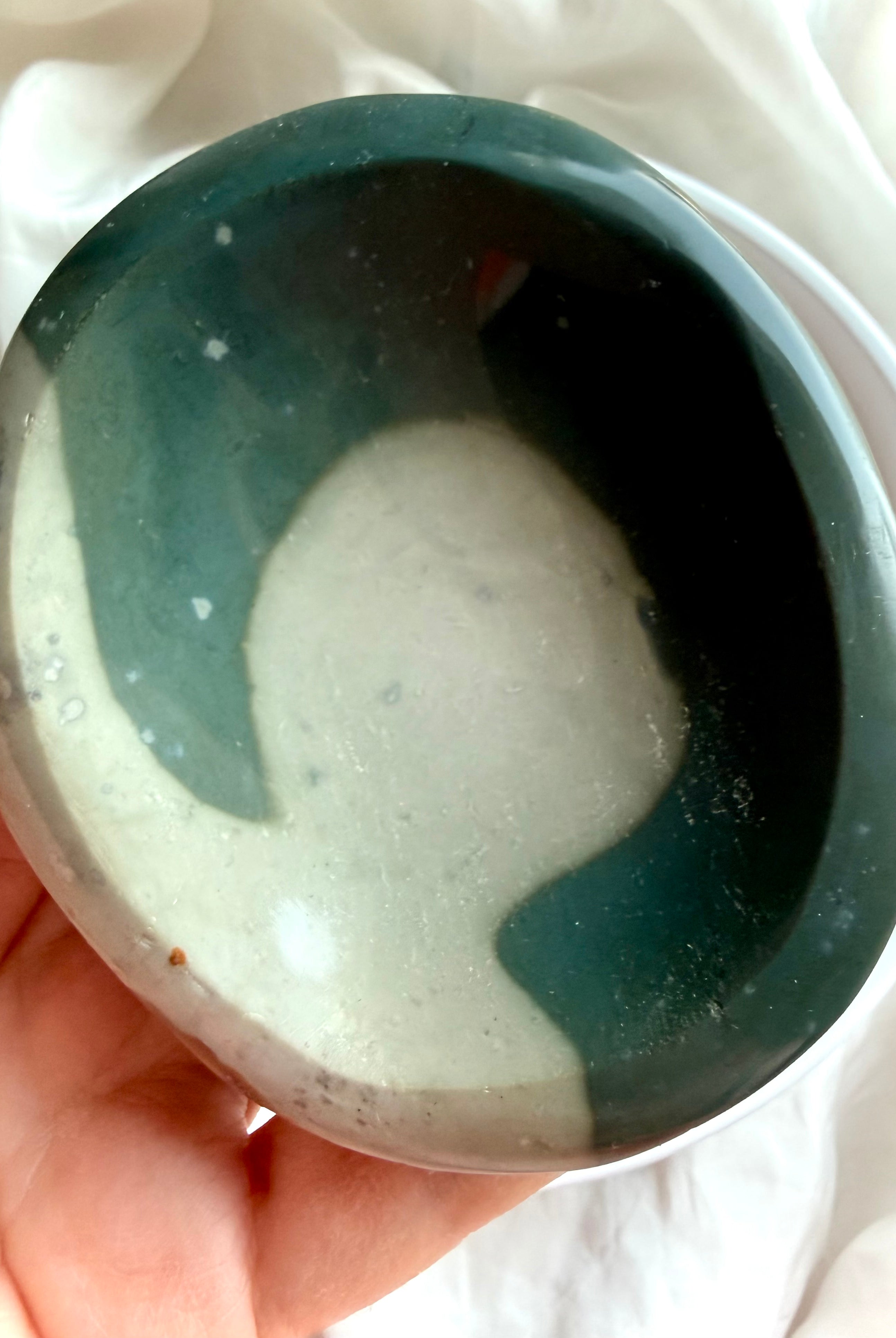 close up of a polychrome jasper bowl in hand showing size and smooth polished shallow shape