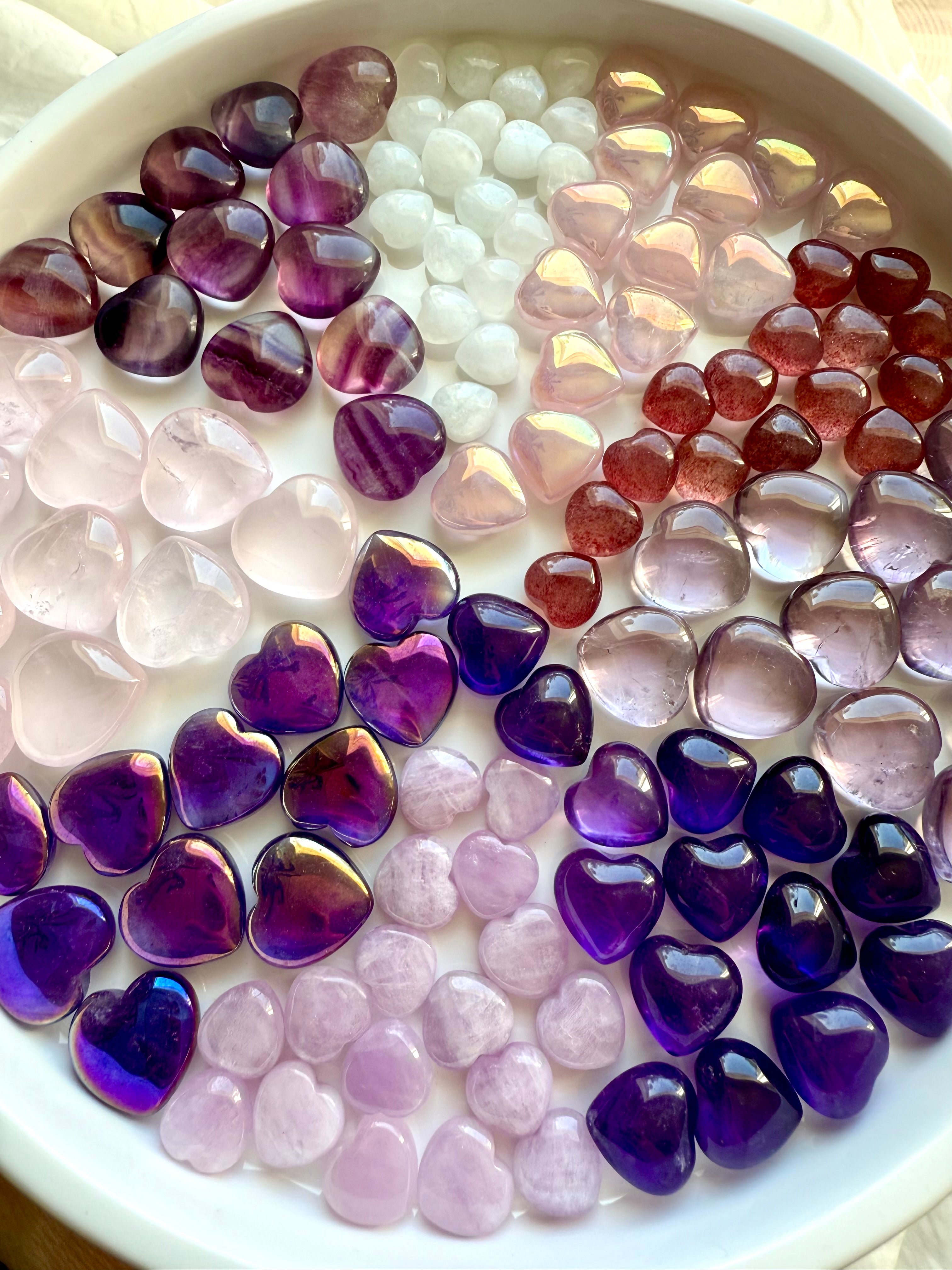 Multiple pink and purple mini crystal hearts arranged in pie-slice formation by stone type, premium carved gemstone hearts.