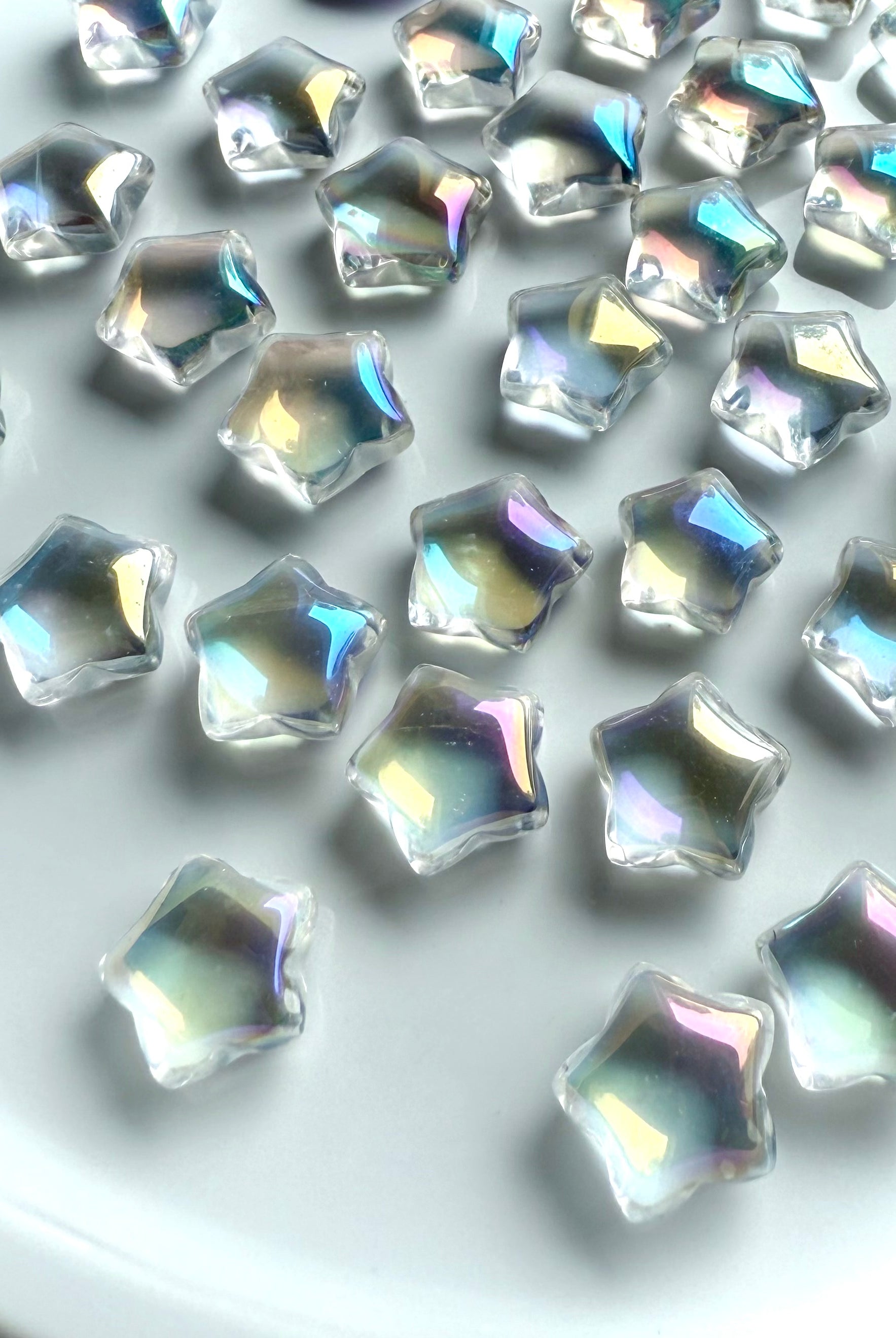 Rainbow aura quartz mini star carvings with iridescent rainbow sheen, polished crystal stars on white background for chakra healing, crystal grids, and altar décor