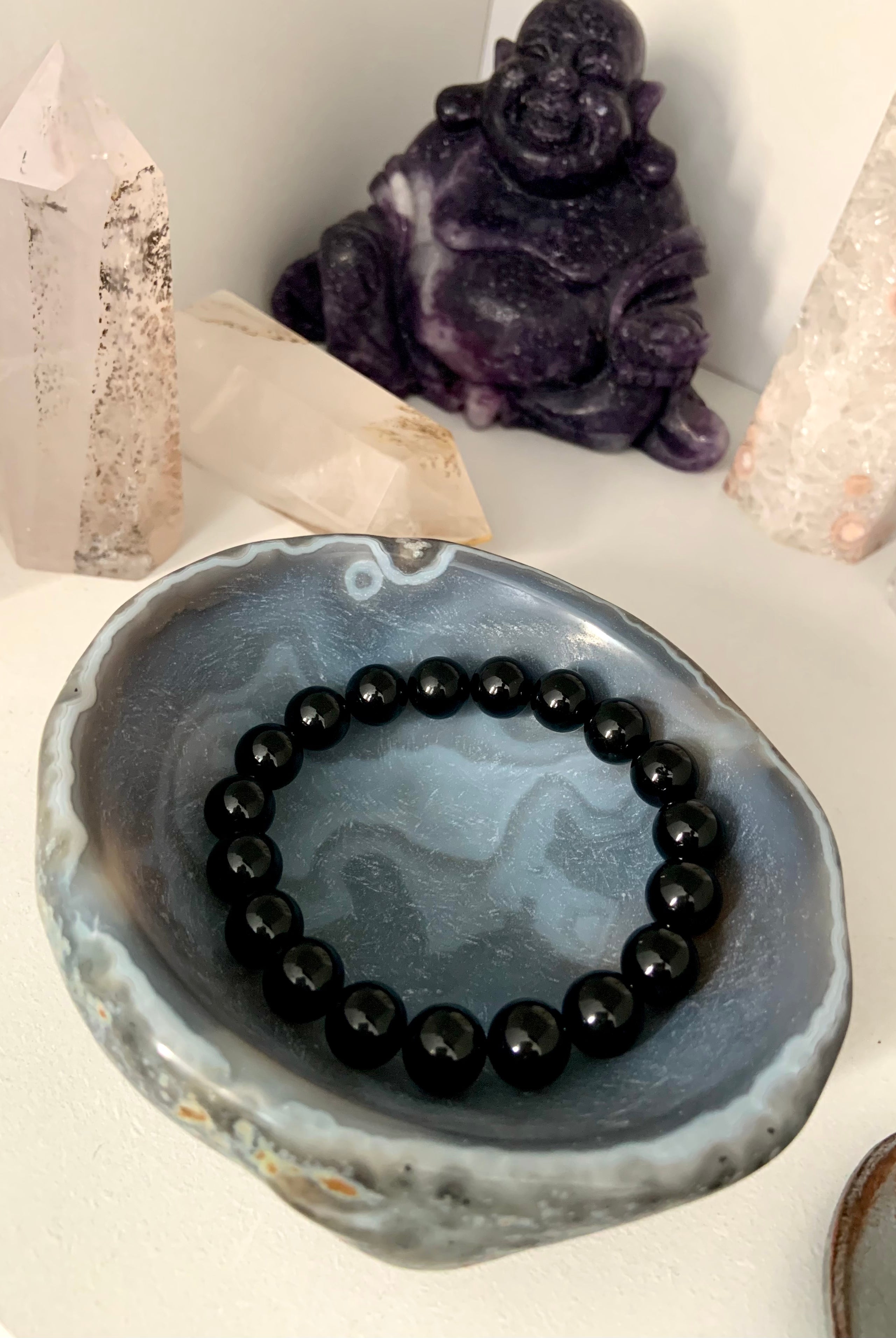 Lifestyle image of a Black Tourmaline bracelet displayed inside a polished agate bowl with other healing crystals — protective crystal jewelry scene