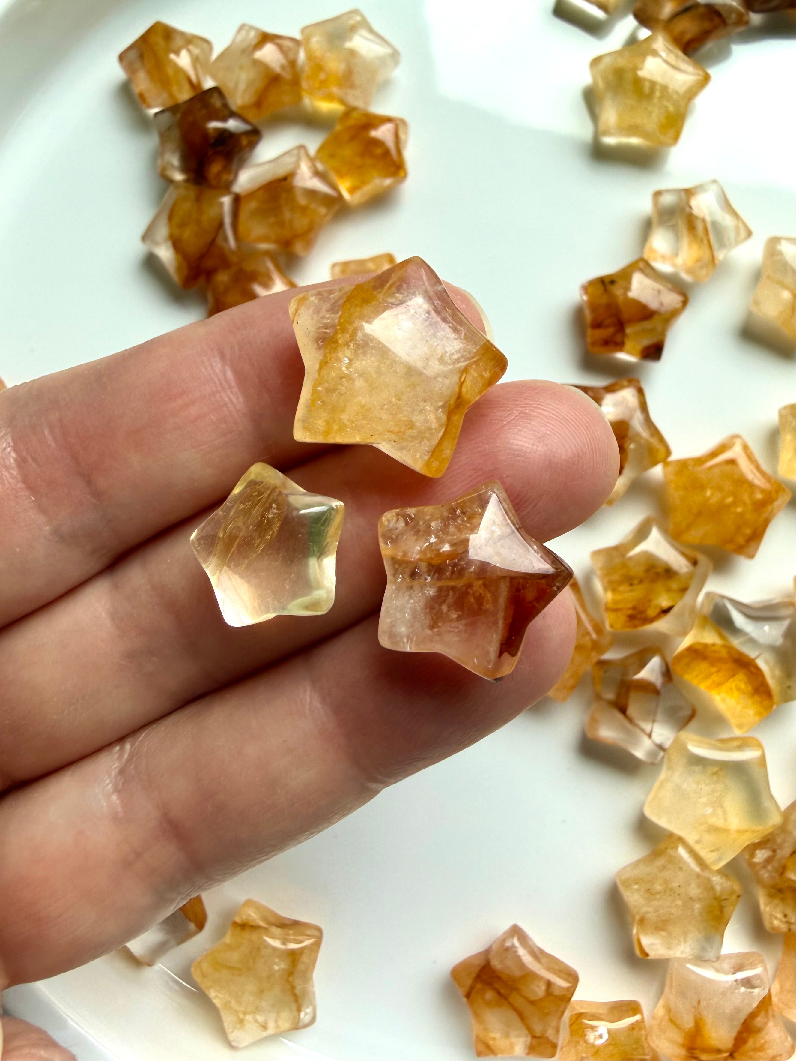 Golden Healer Quartz star crystal carvings held in hand showing golden yellow Hematoid patterns and polished finish