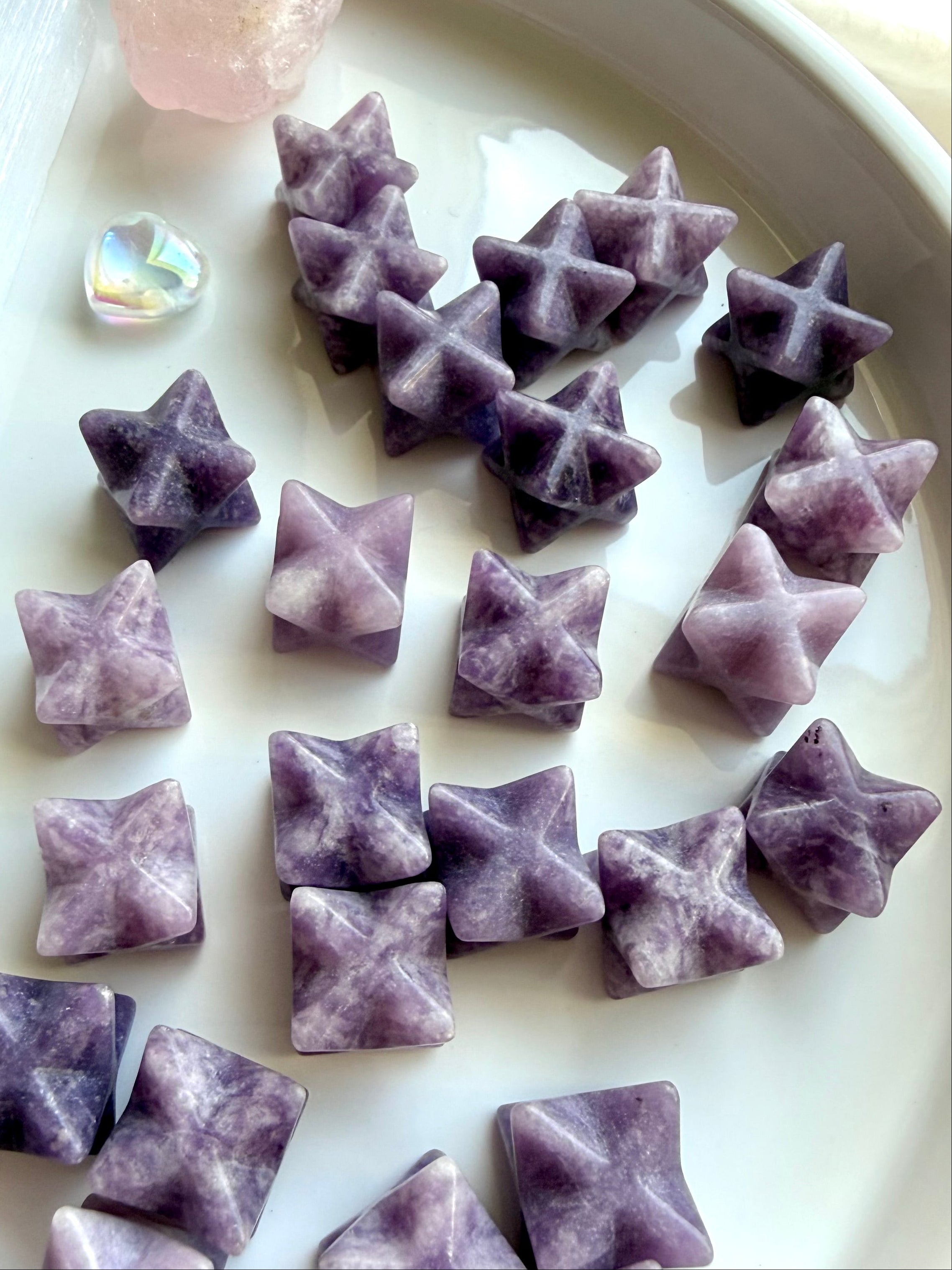 lepidolite merkaba star carvings assortment on marble surface, mini purple crystal stars for calm emotional balance and stress relief