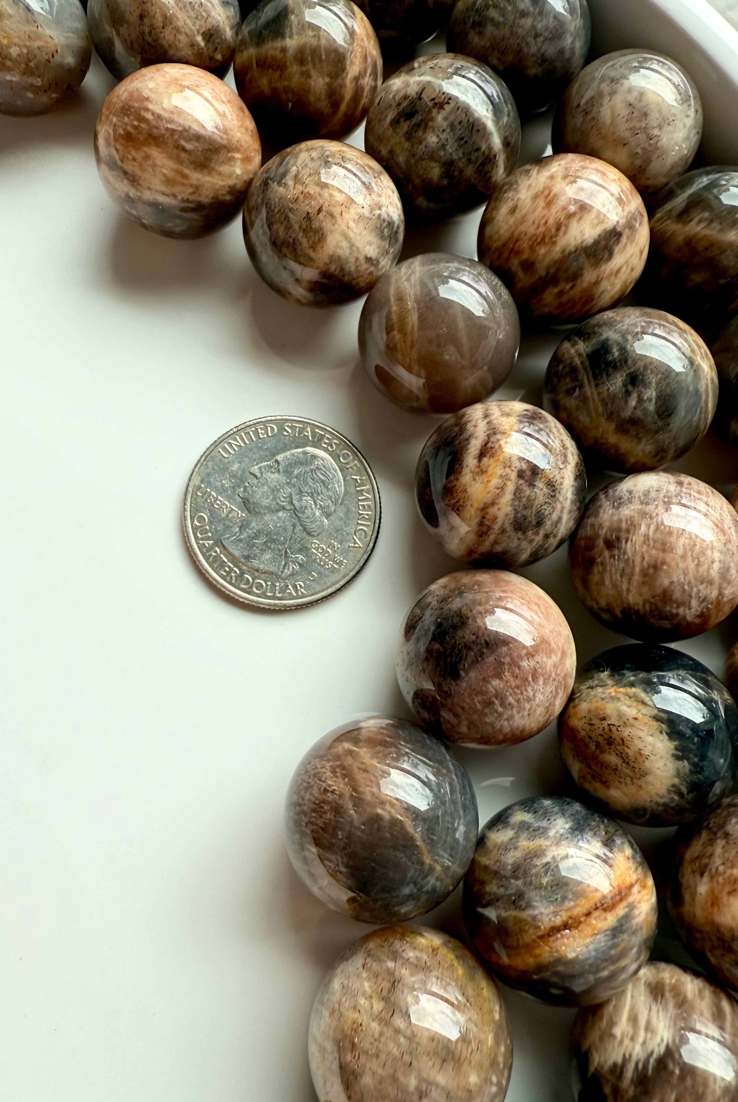 Mini Black Moonstone spheres shown with a quarter for scale, metaphysical properties for intuition & grounding