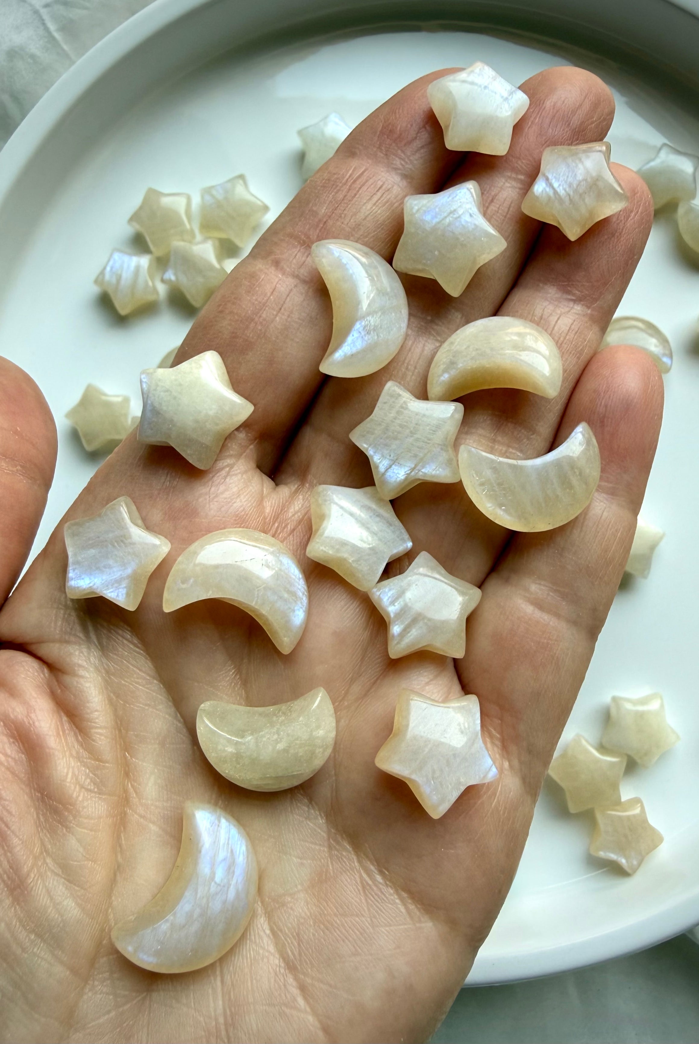 Moonstone moon and star crystal carvings displayed in hand showing size and flash