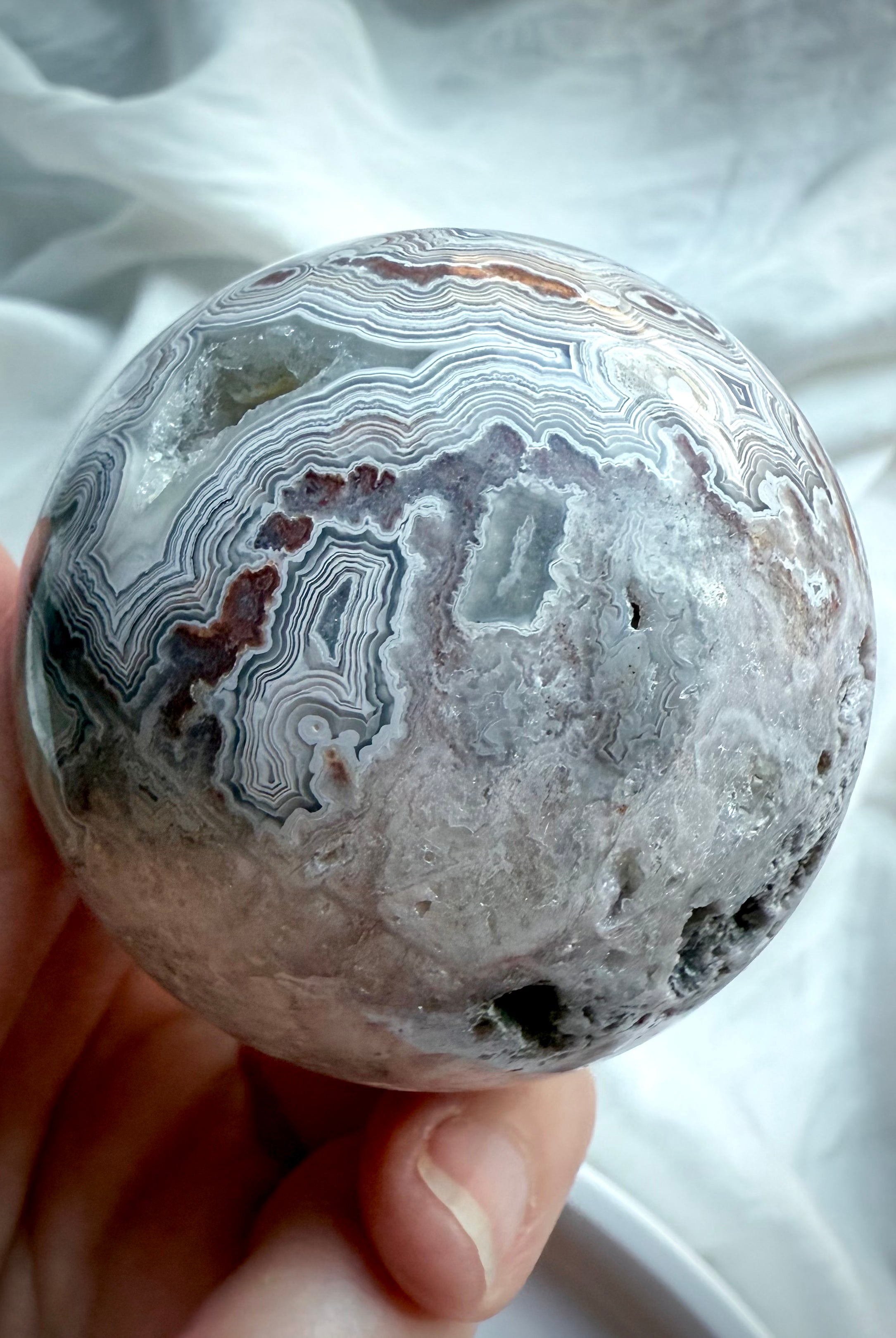 Natural agate crystal sphere with swirling bands, crystalline pockets, and earthy neutral tones for grounding energy work