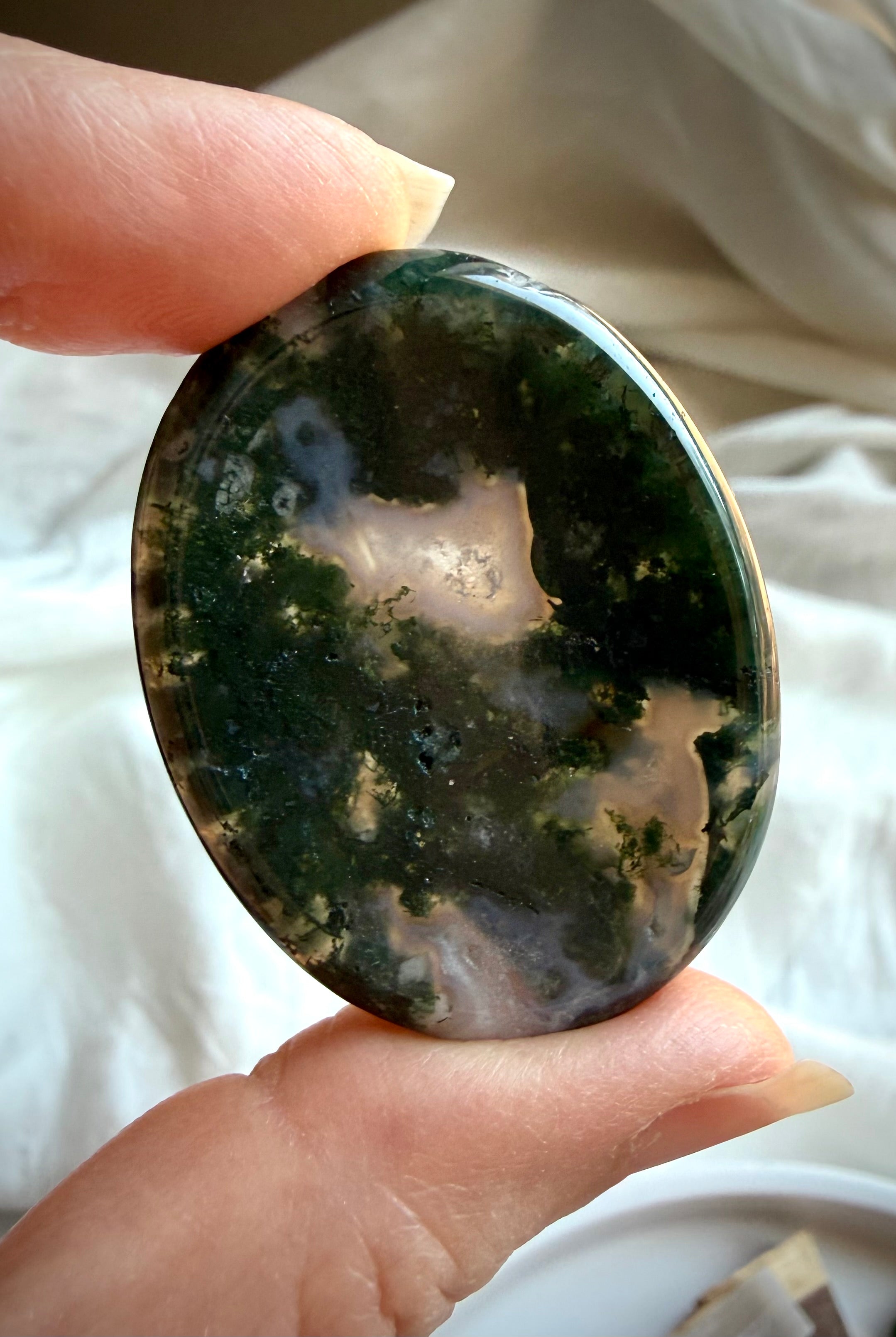 Moss Agate oval thumb stone held in hand with rich moss inclusions and translucent quartz