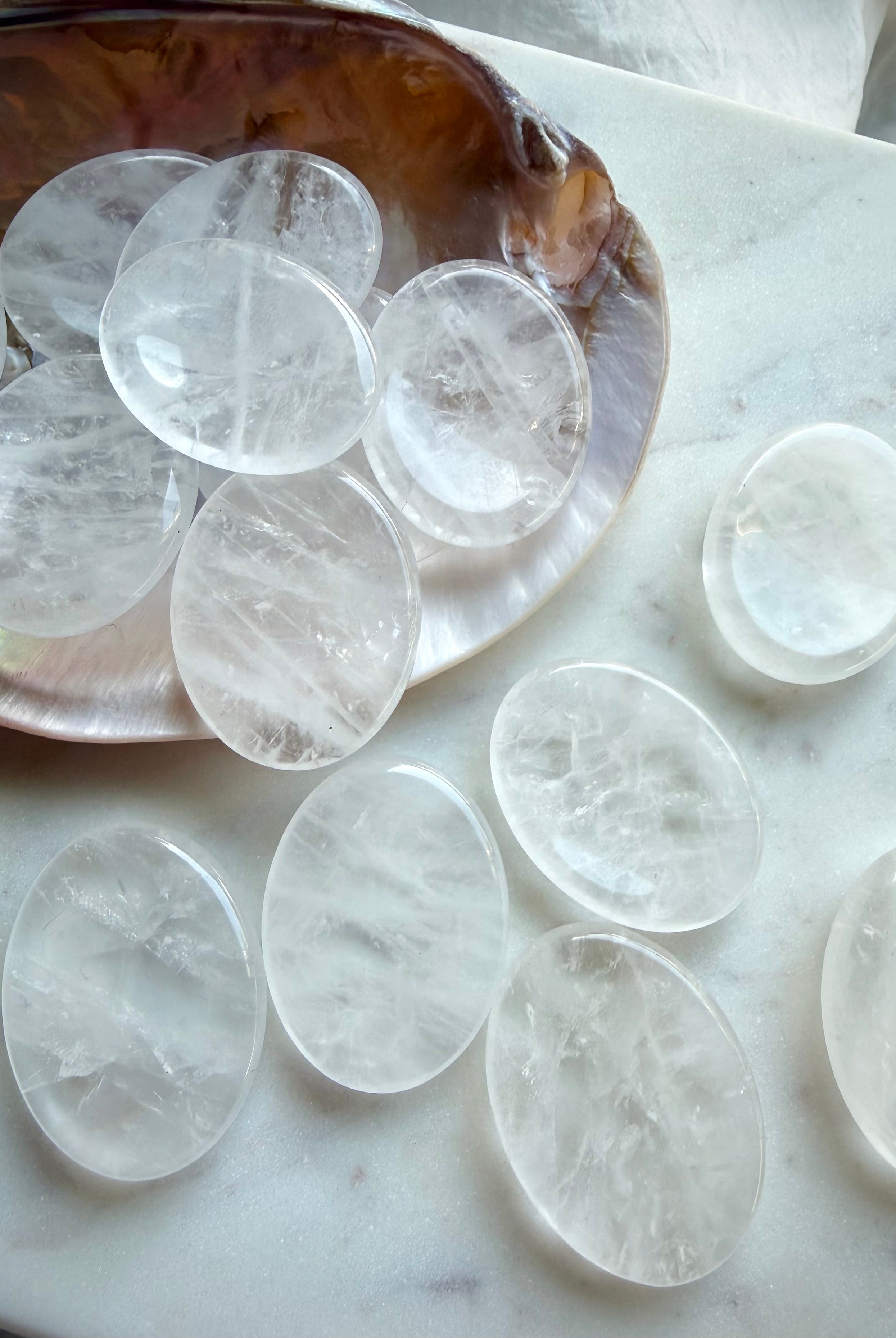 clear quartz worry stones on seashell dish on marble oval thumb stones for clarity focus and energy