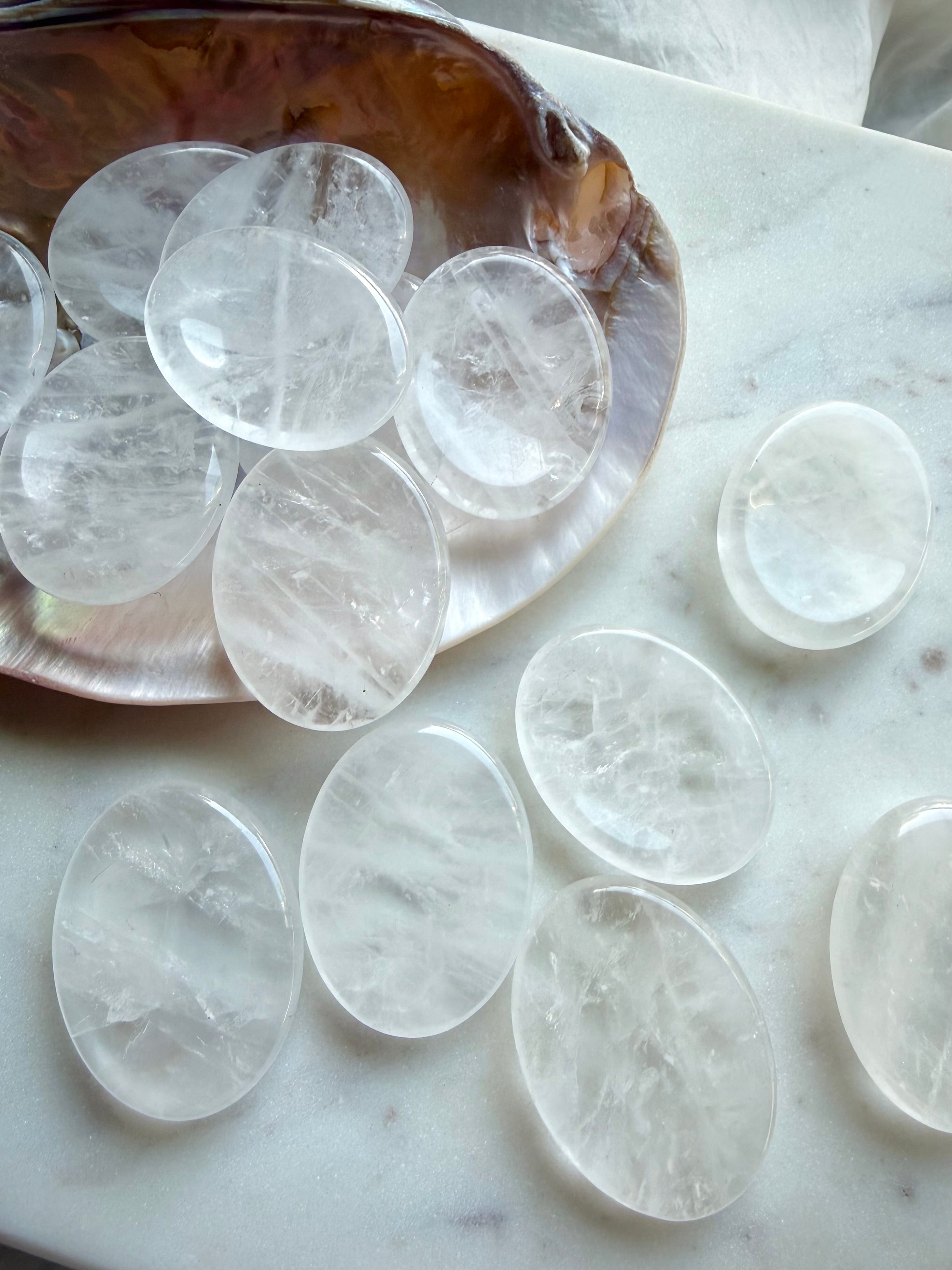 clear quartz worry stones on seashell dish on marble oval thumb stones for clarity focus and energy