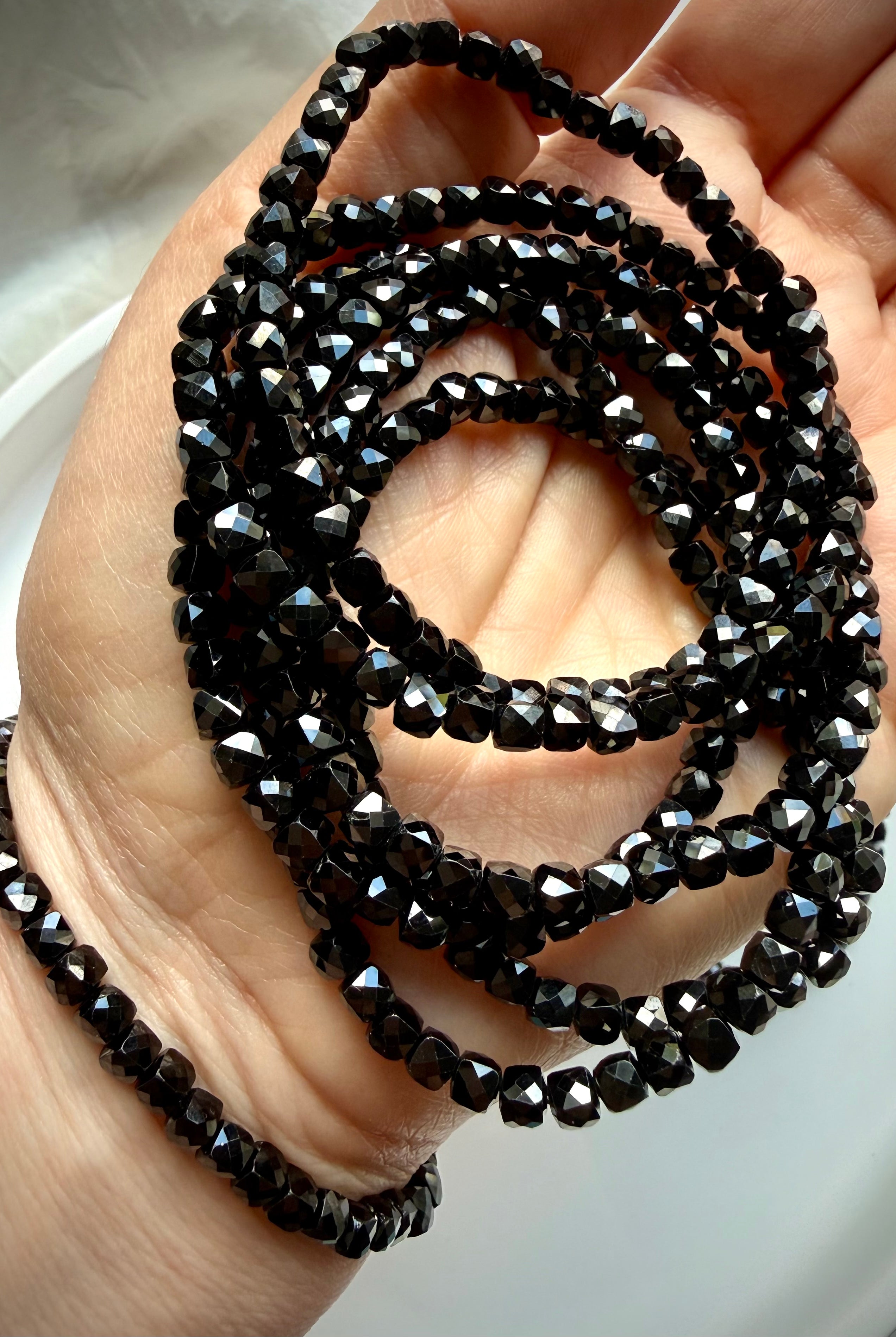 stacked black spinel bracelets on hand for grounding protection and everyday wear