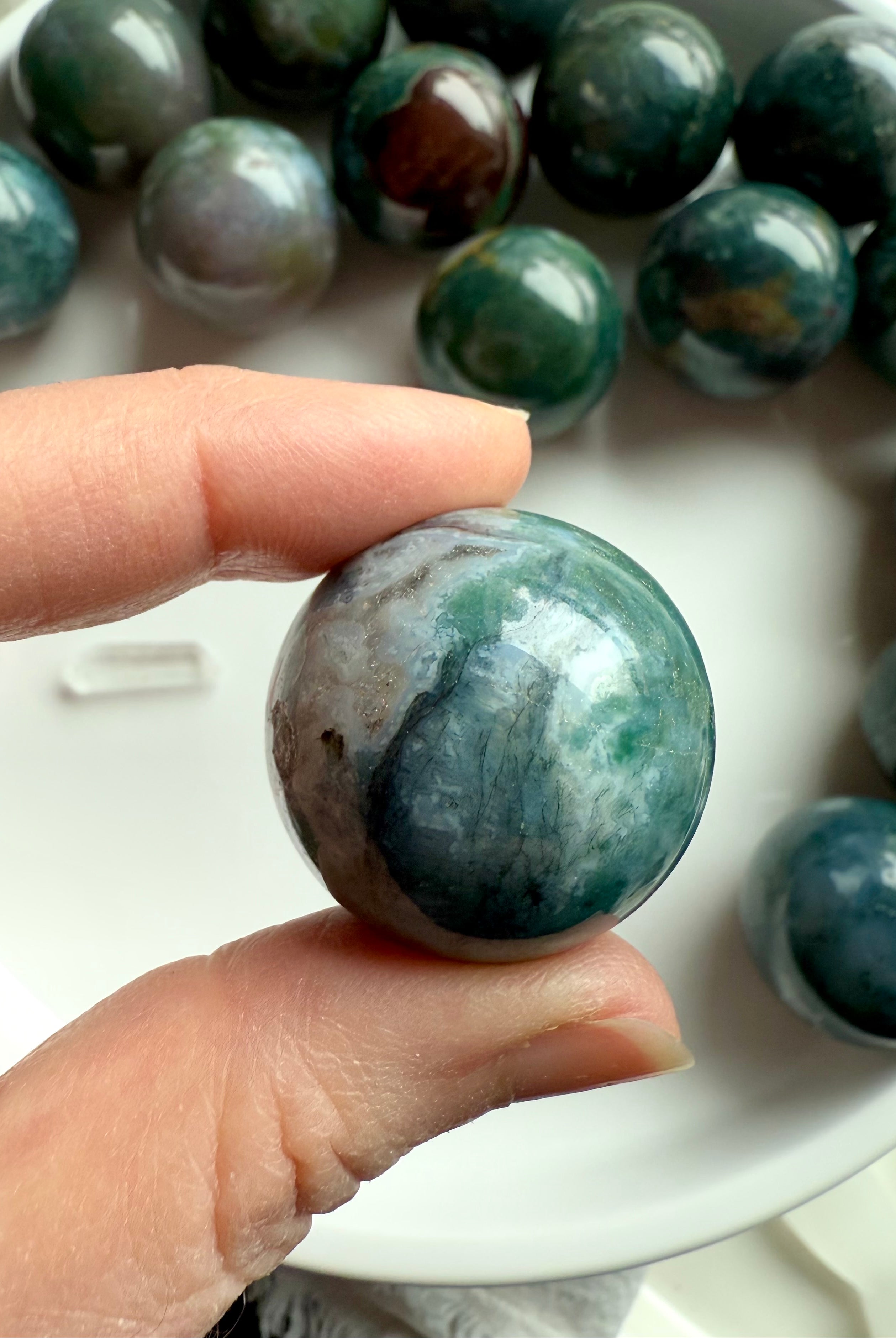 Colorful moss agate mini spheres shown held between my fingers for scale