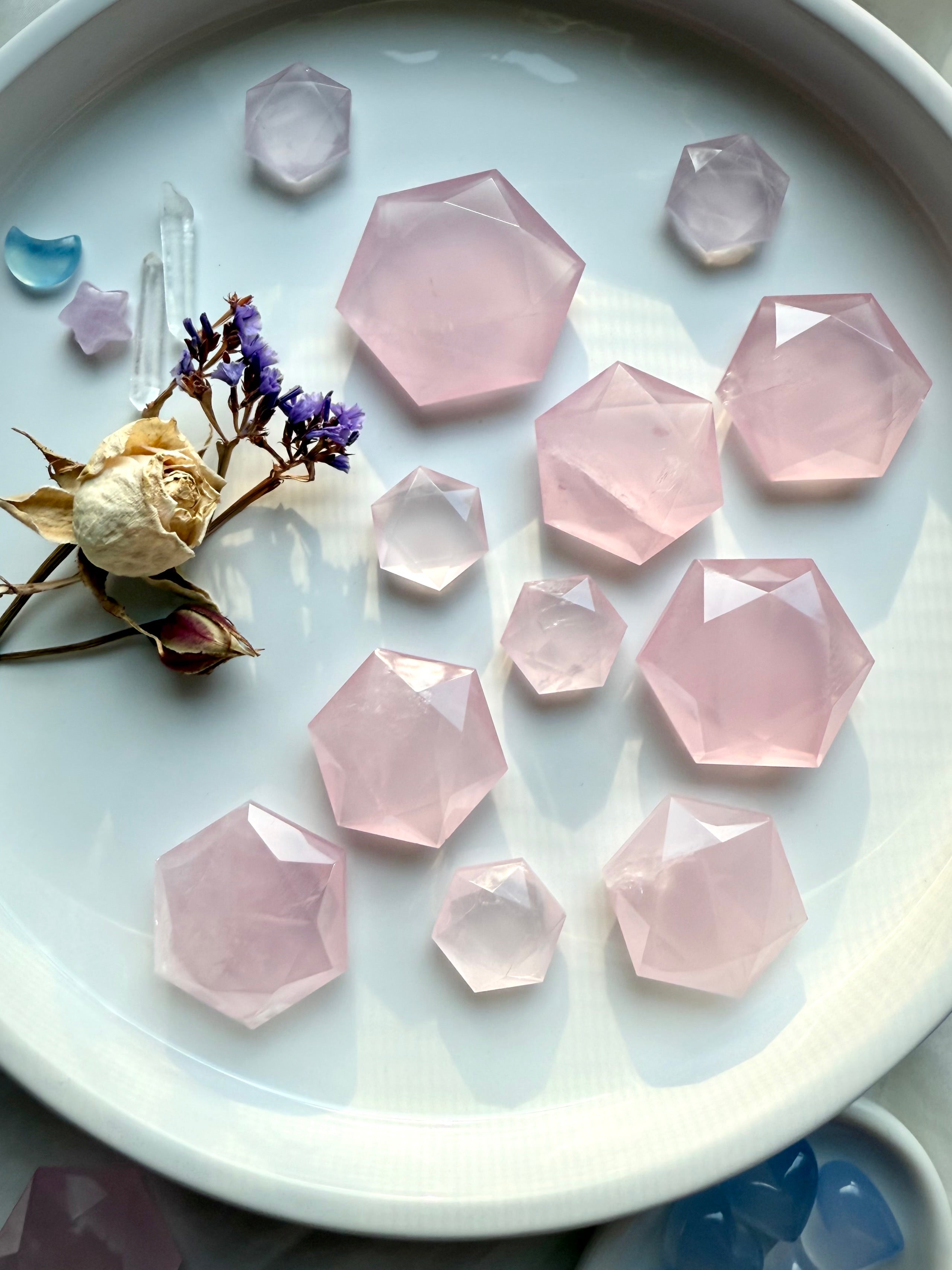 A plate of rose quartz hexagon crystals with roses, clear quartz points and celestial gems, sacred geometry carvings for grids or décor