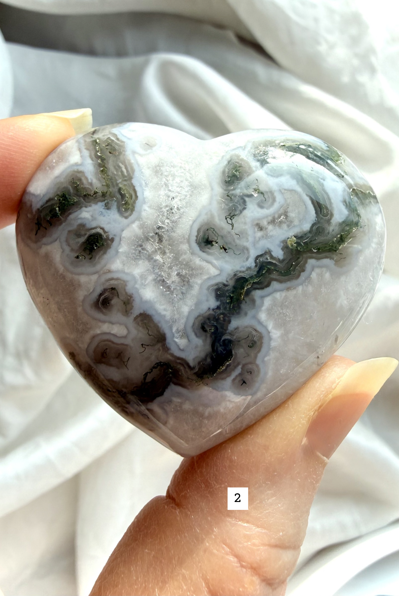 moss agate heart carving option 2 in hand showing quartz inclusions and earthy green mineral inclusions