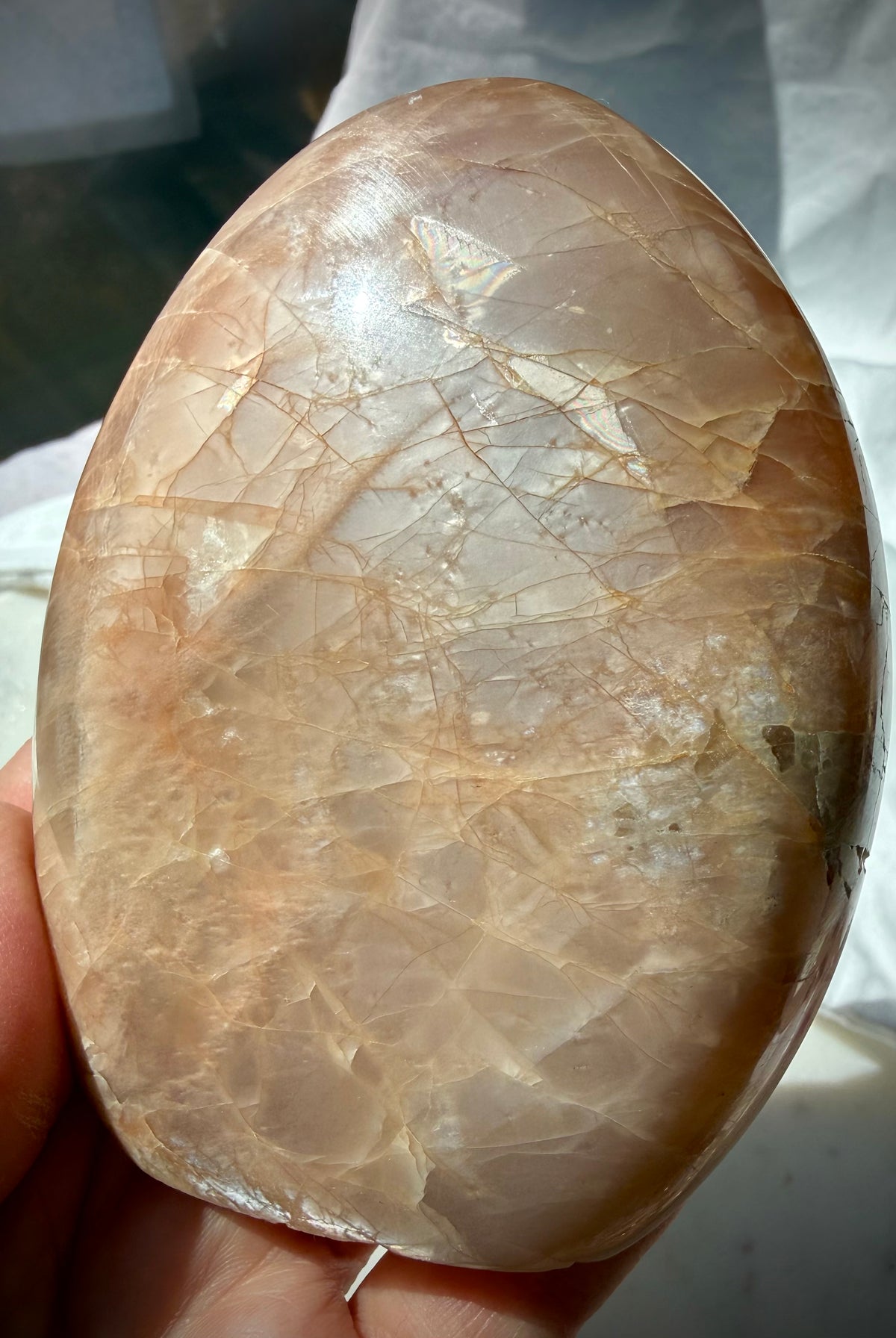 Peach Moonstone with Sunstone shimmer showing golden sparkle, silvery glow and rainbow flashes across the polished crystal