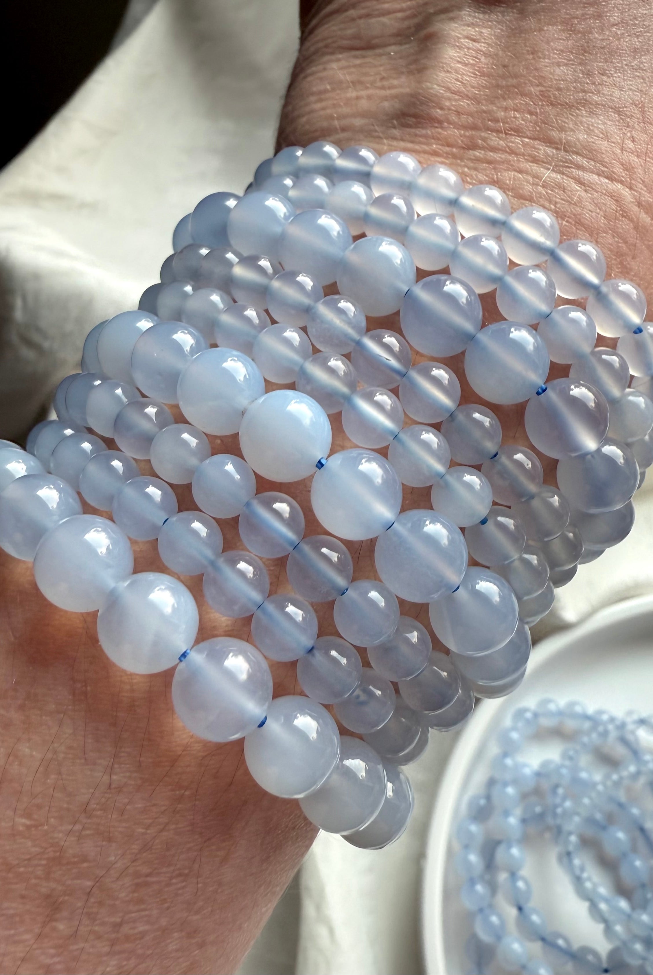 Light blue Blue Chalcedony bracelet beads on wrist, reflecting soft light with ethereal translucence