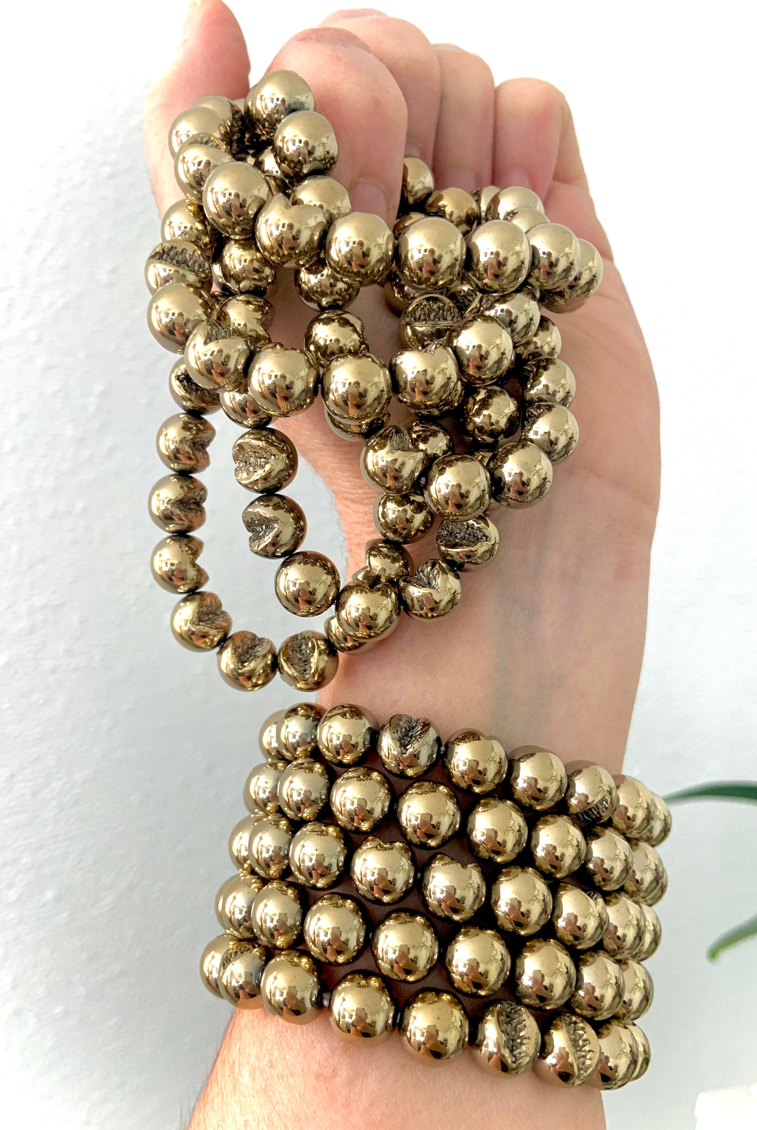 Wrist adorned with stacked Pyrite bracelets — crystal jewelry for abundance, protection & manifestation