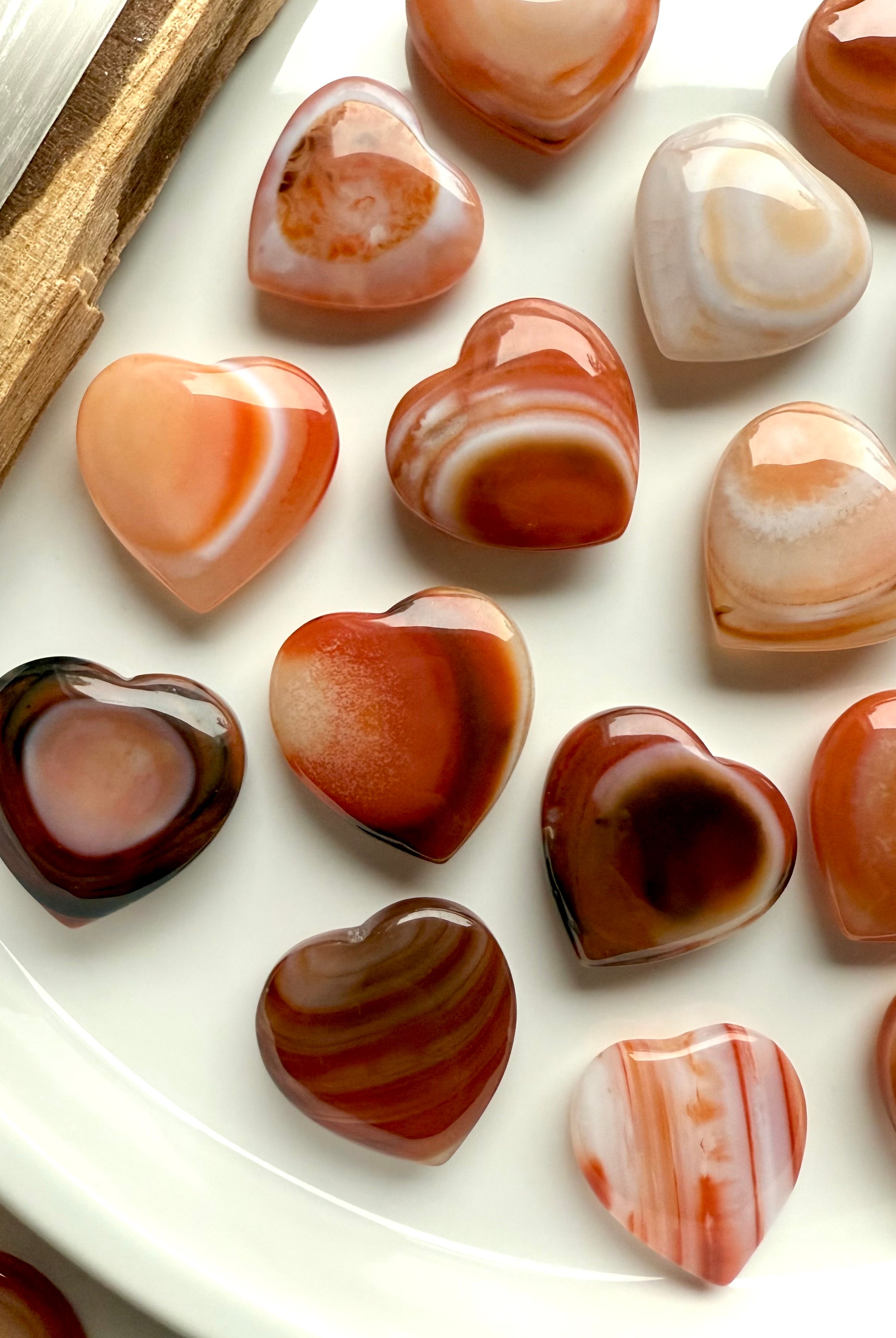 Mini Carnelian heart crystals showing natural banding and warm orange tones, sacral chakra stones for creativity, joy, and motivation