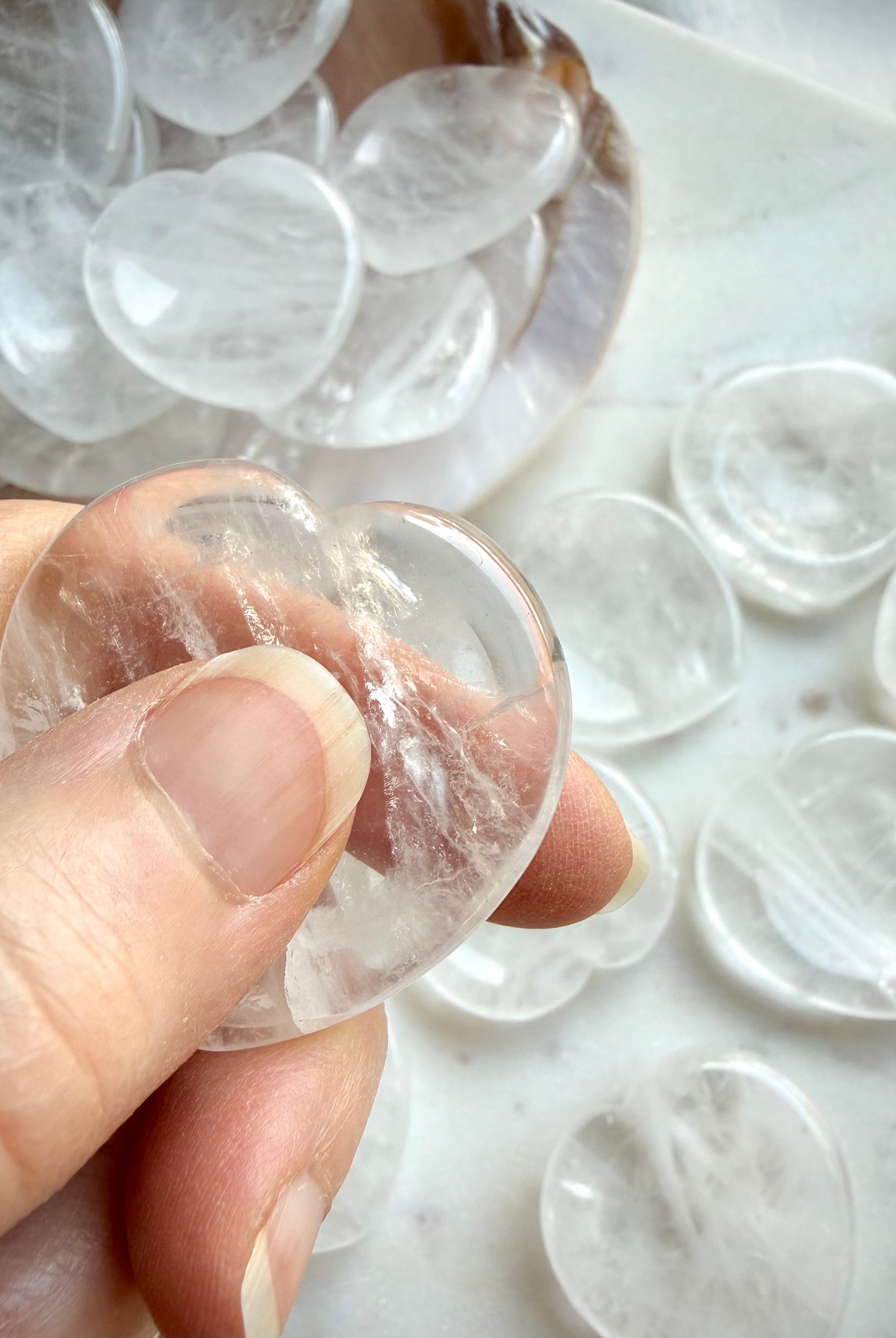 clear quartz heart worry stones in hand showing smooth polished thumb stone shape for calming energy
