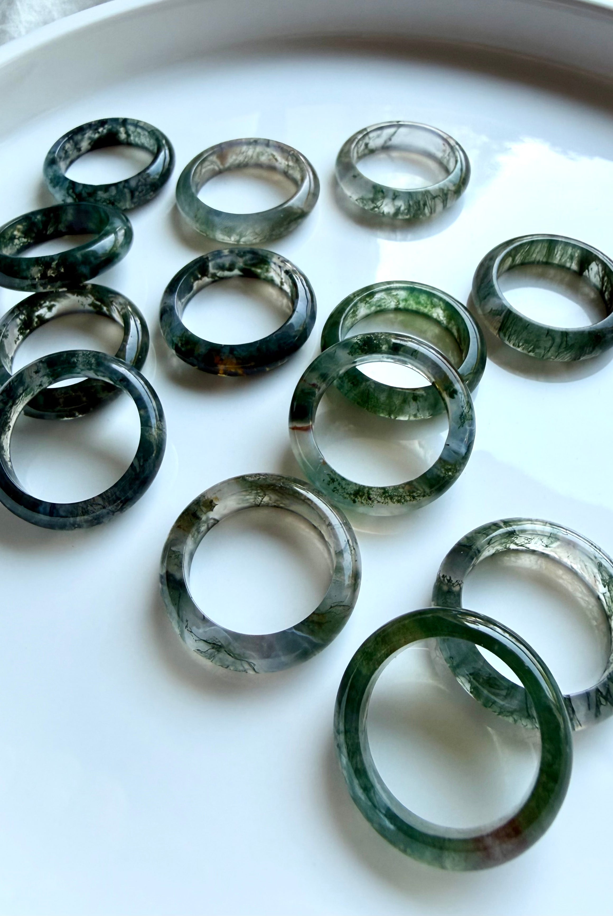 moss agate rings arranged on white with organic green inclusions, crystal band rings for heart chakra and stability