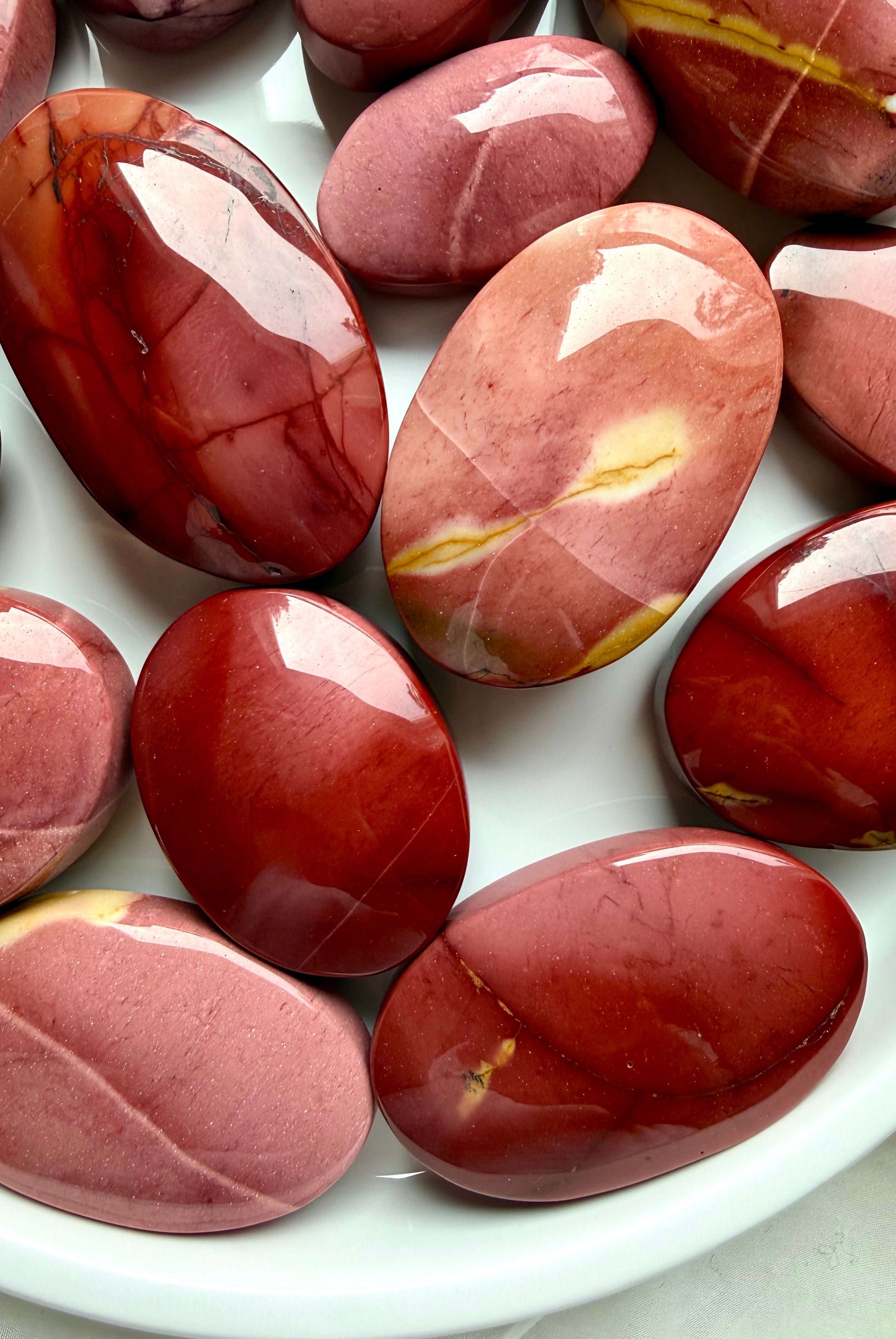 glossy Mookaite Jasper palm stones with natural cream and crimson patterns for root chakra grounding and vitality