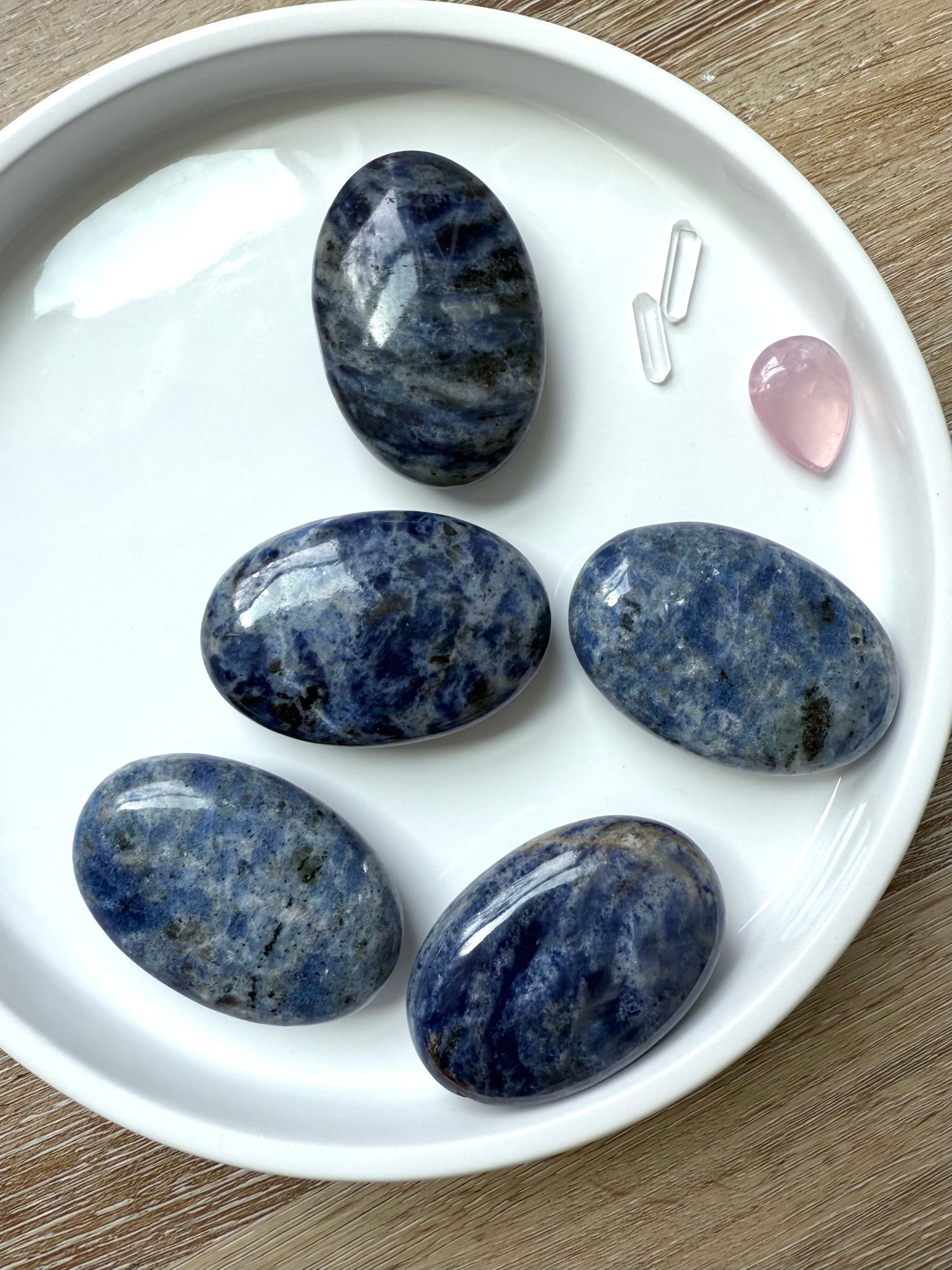 An array of high quality blue Sodalite Palm Stones shown on a white plate