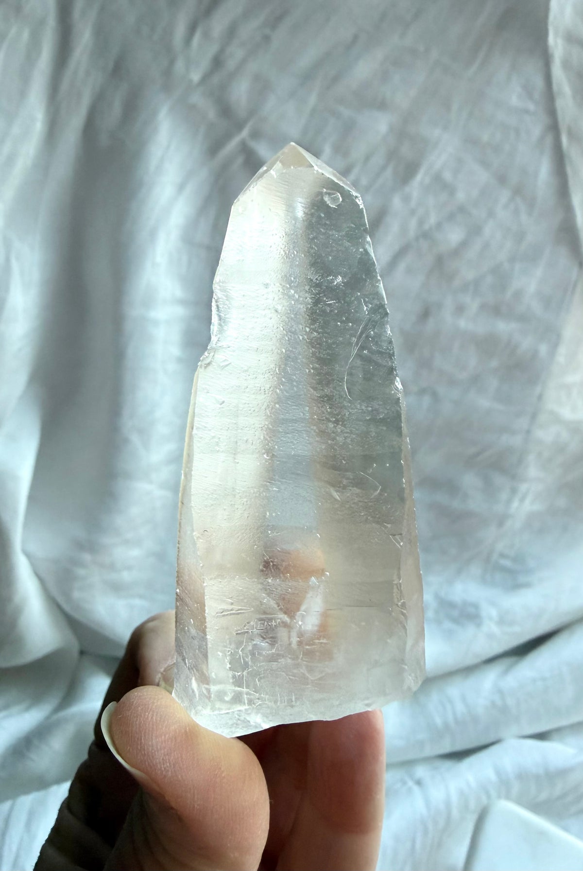 Large Lemurian Quartz point held in hand showing natural ladder lines, internal veils, and a clear crystal termination