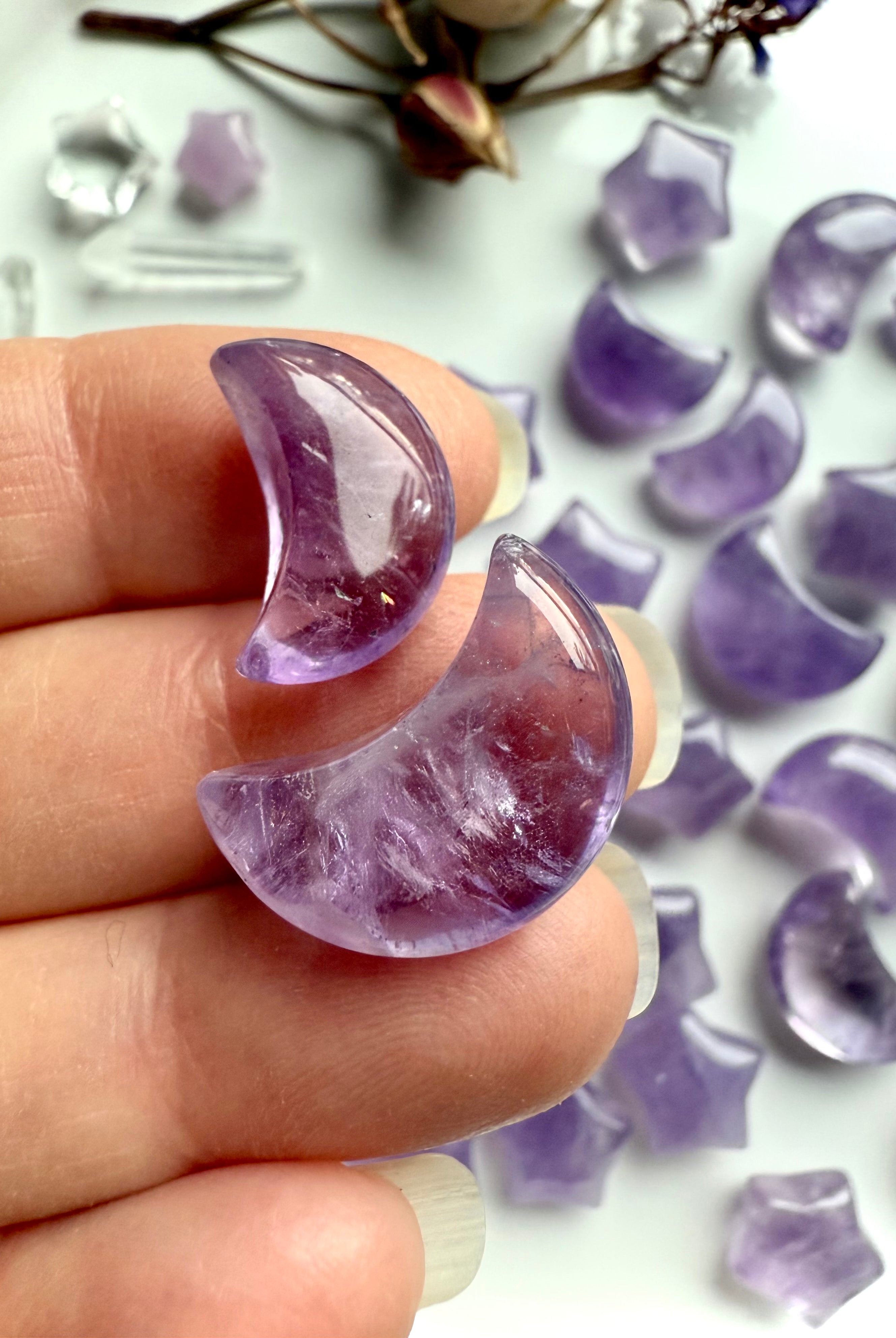 Closeup view of a two amethyst moon crystal carvings with translucent purple tones