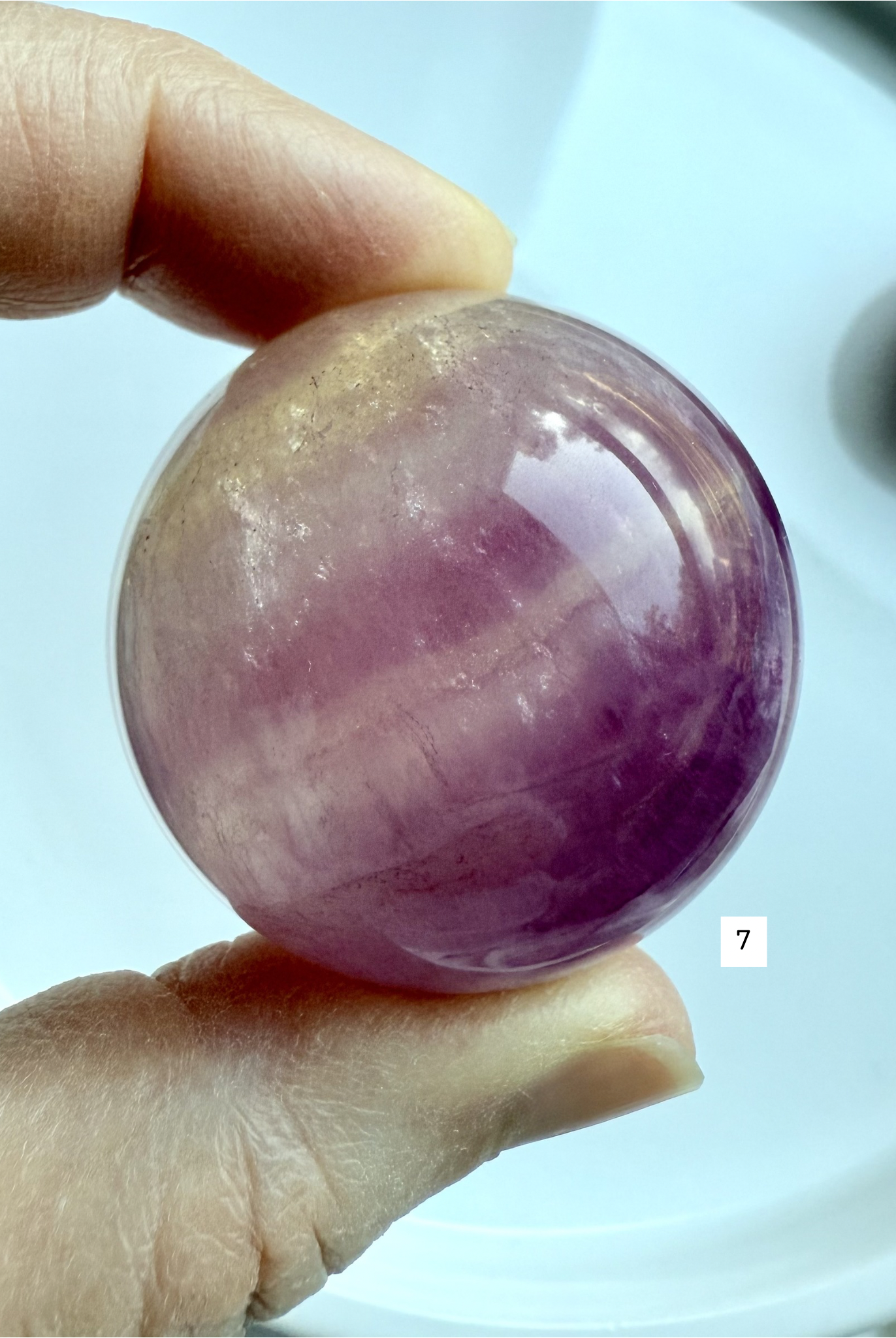 high grade Silky Magenta Fluorite crystal sphere with rich violet and pink color zoning held in hand