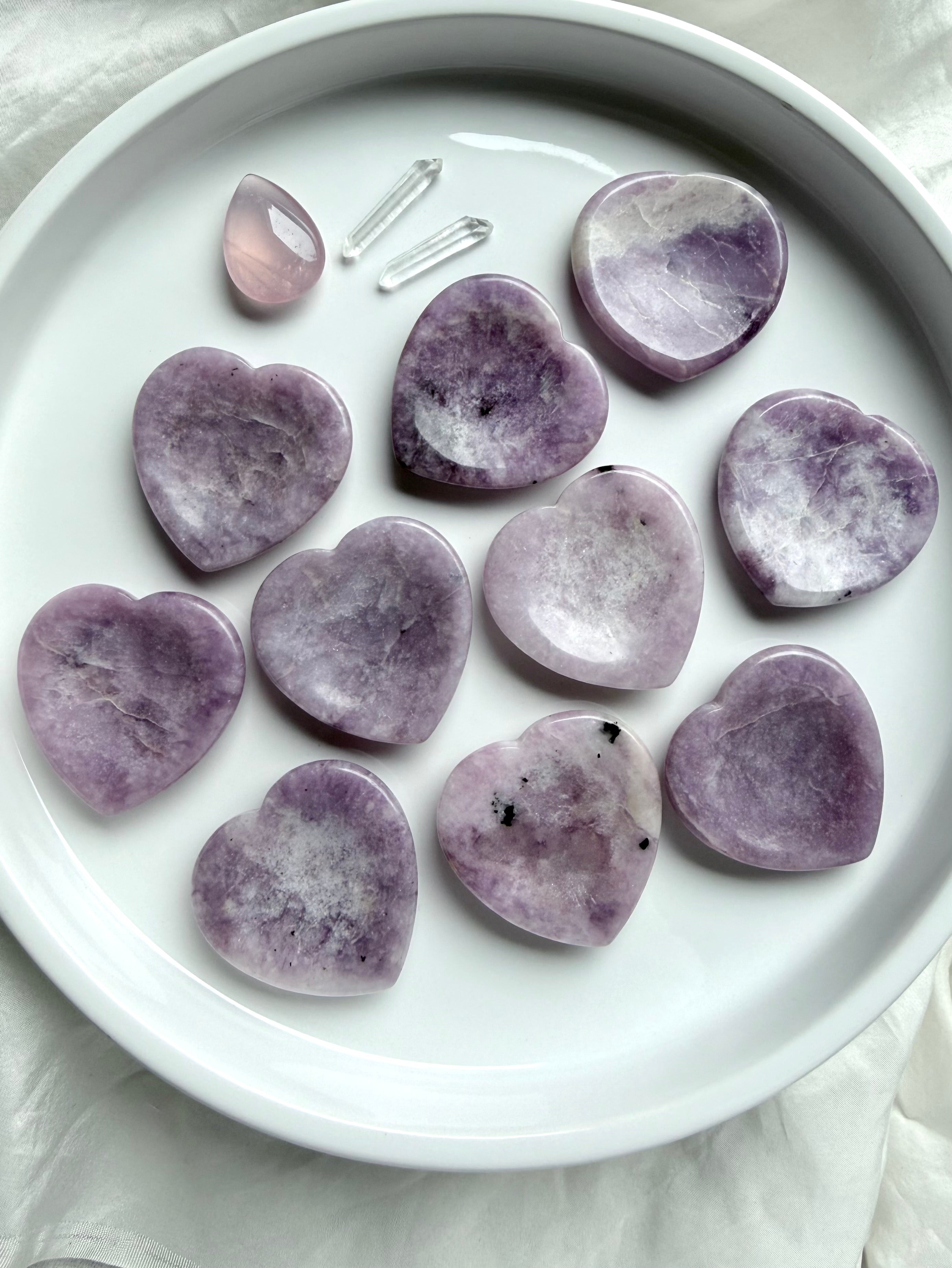 Lepidolite heart worry stones styled on white tray in natural light calming crystal pocket stones