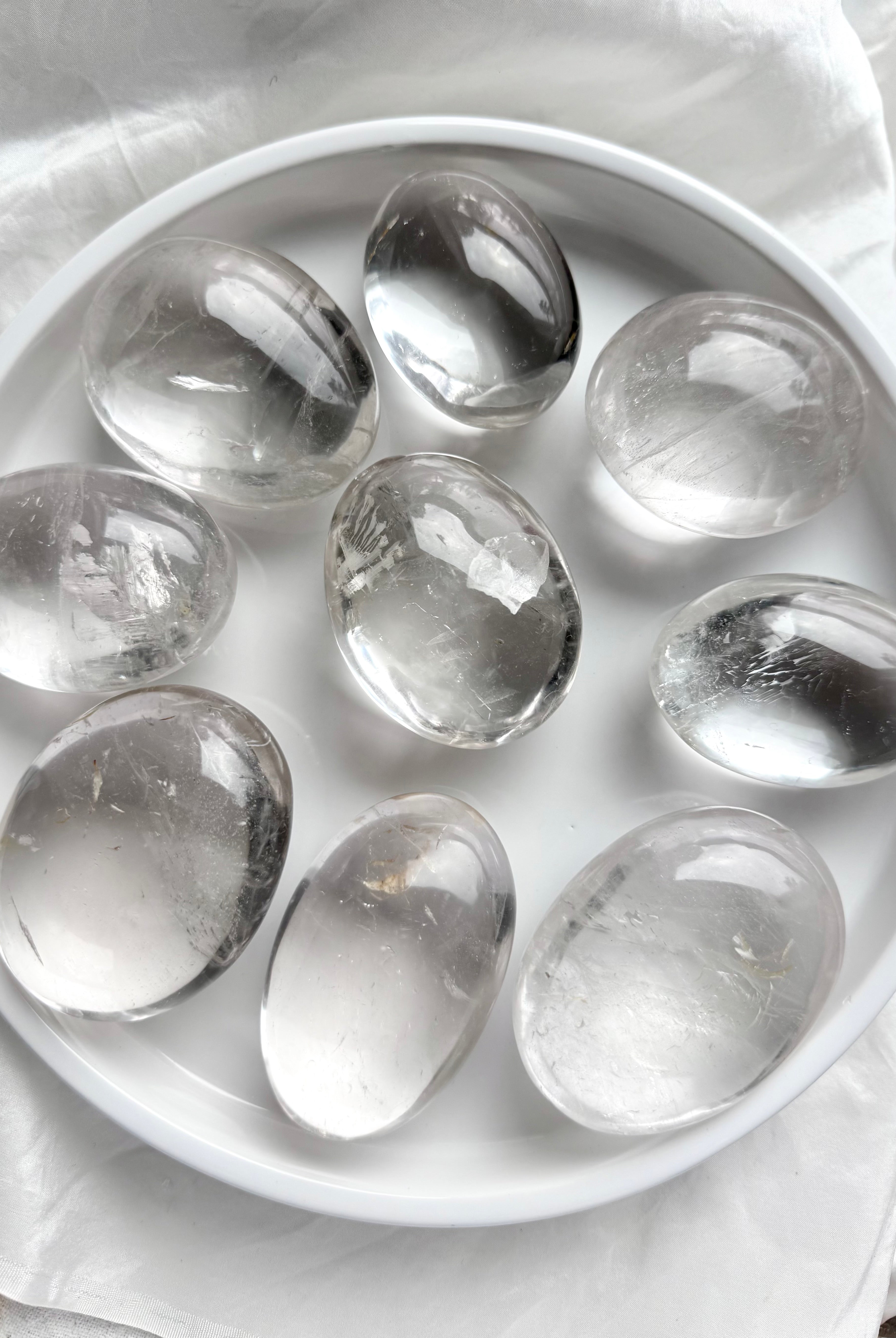 An array of clear quartz meditation stones, smooth polished palm stones for energy work