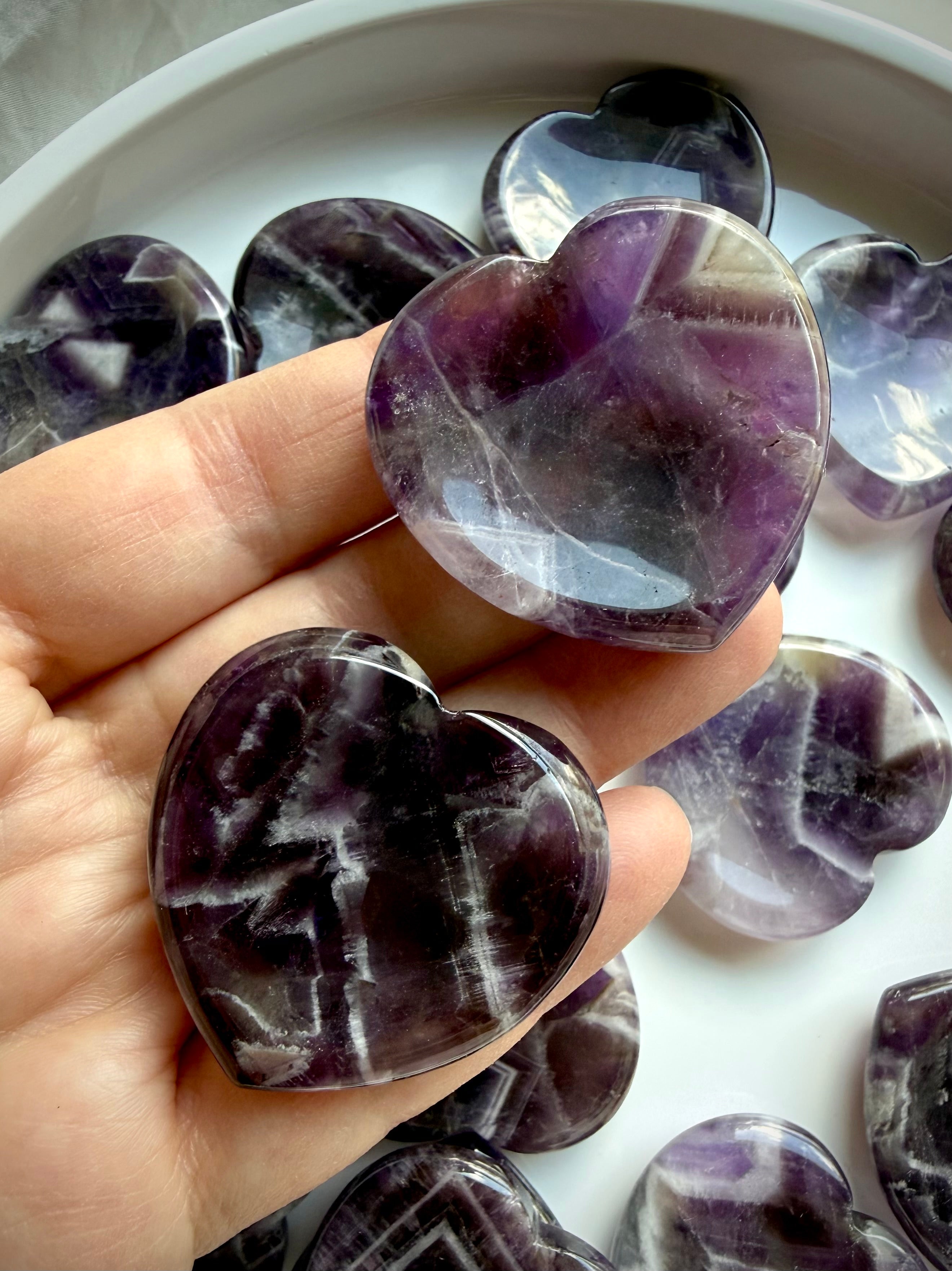 two dream amethyst heart stones in hand for calming energy and stress relief