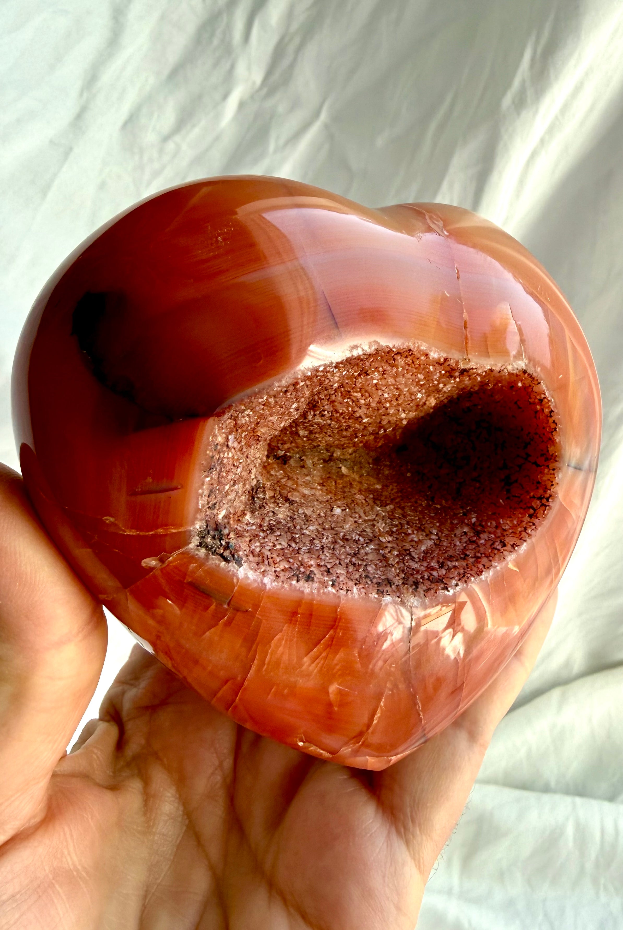Side view of large Carnelian geode heart highlighting sparkling druzy crystal cavity