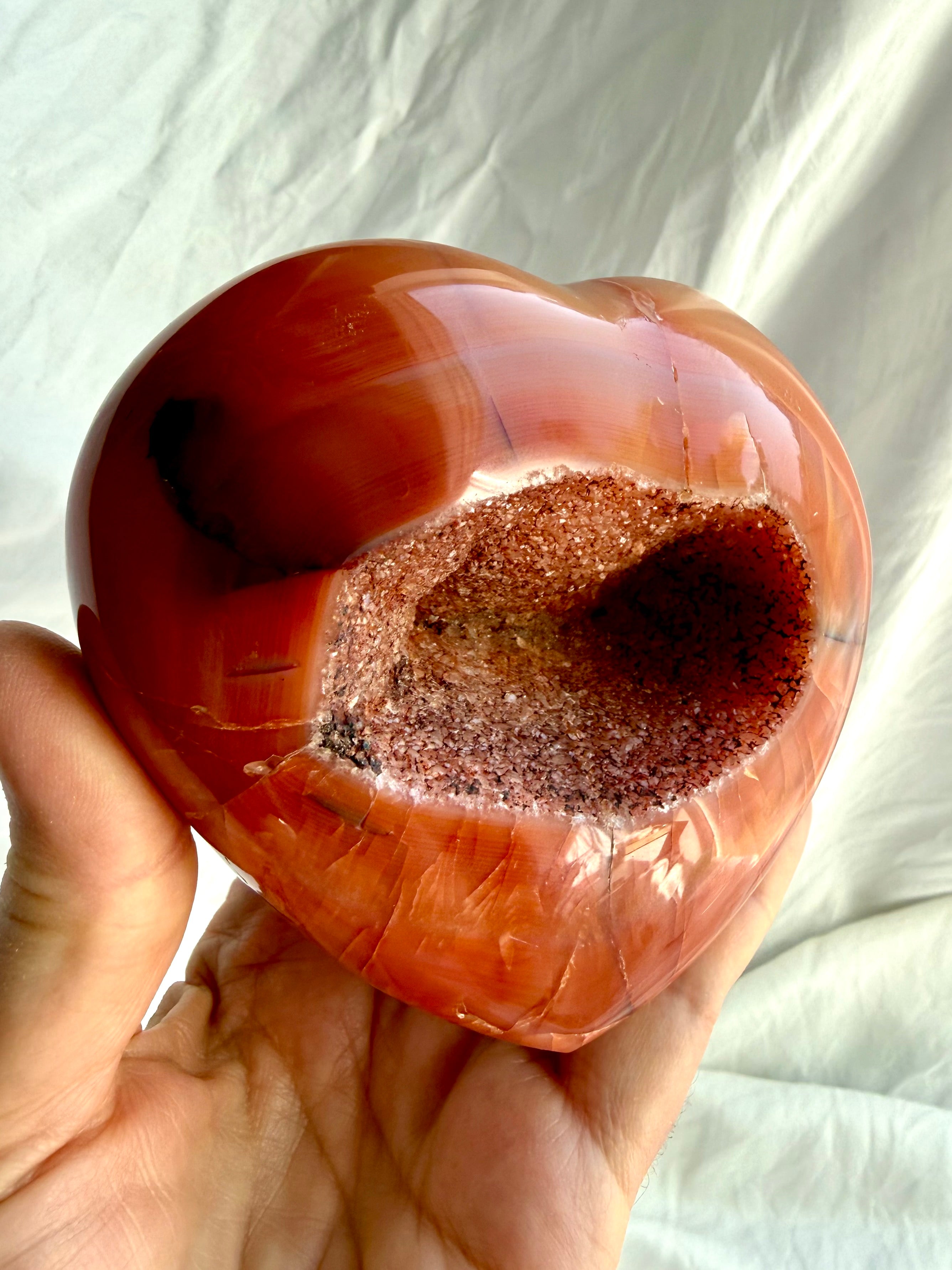Side view of large Carnelian geode heart highlighting sparkling druzy crystal cavity