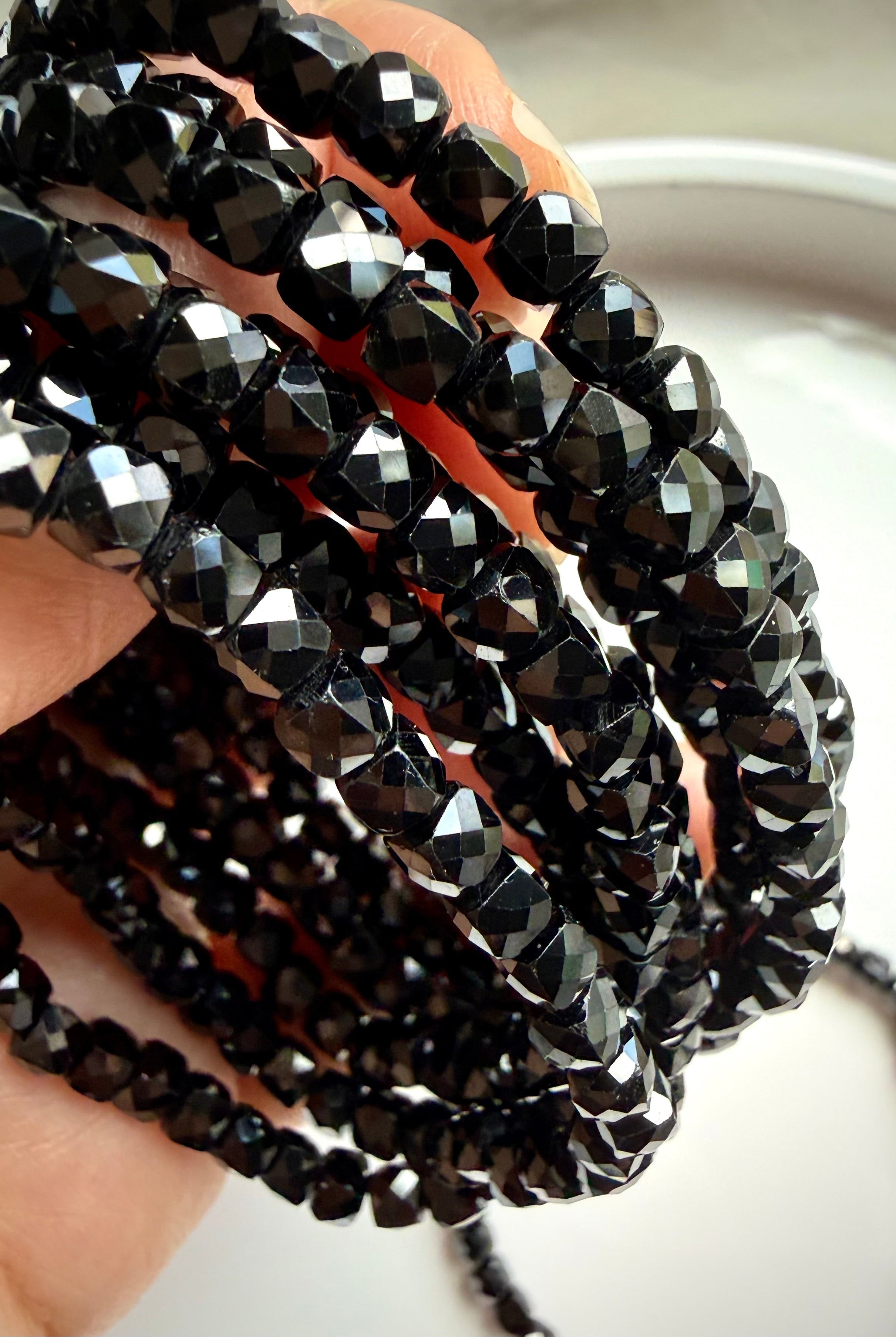 closeup of multiple faceted black spinel bracelets stacked together for grounding and protection
