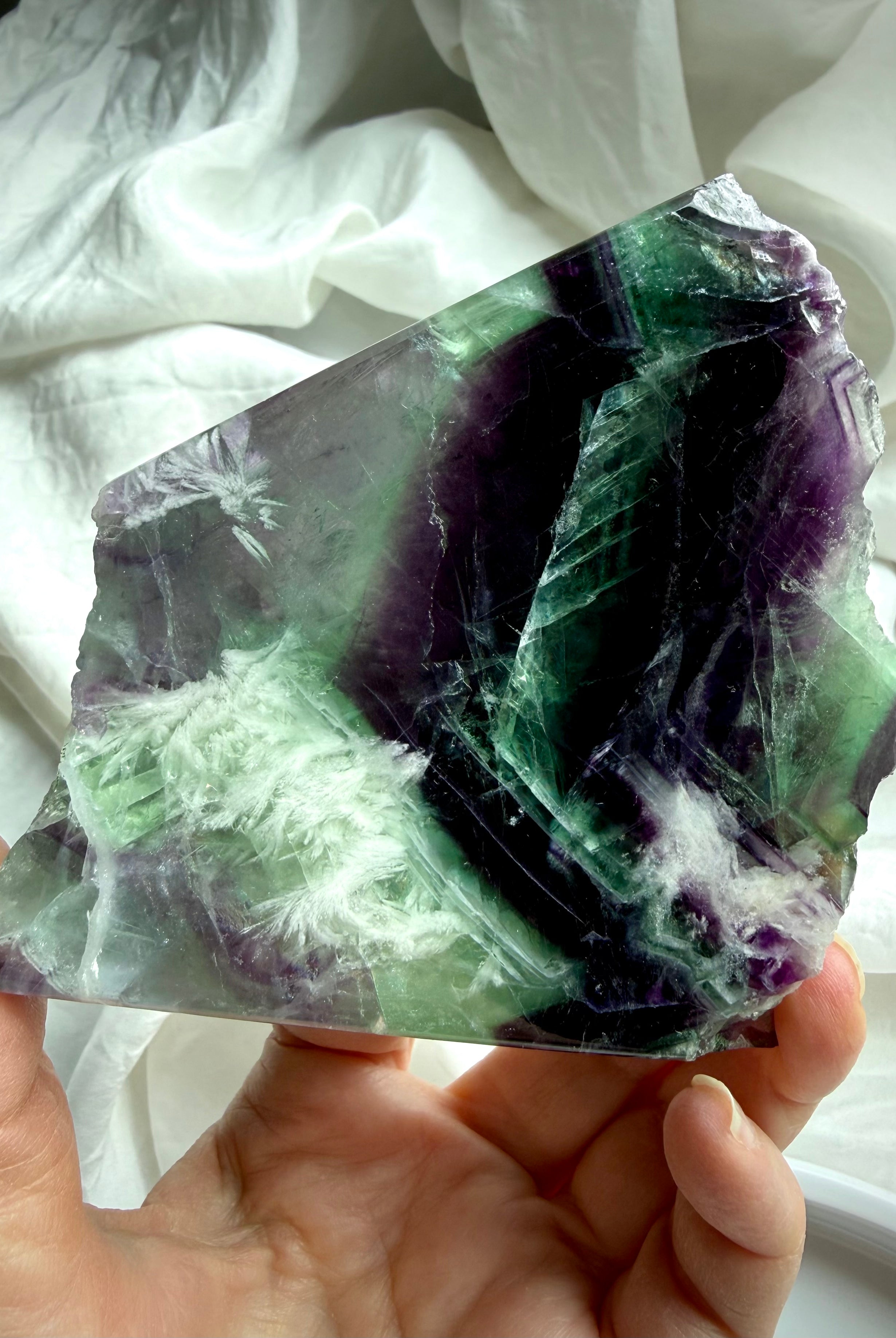 green and purple fluorite slab showing rainbow internal flashes and white scolecite snowflake inclusions