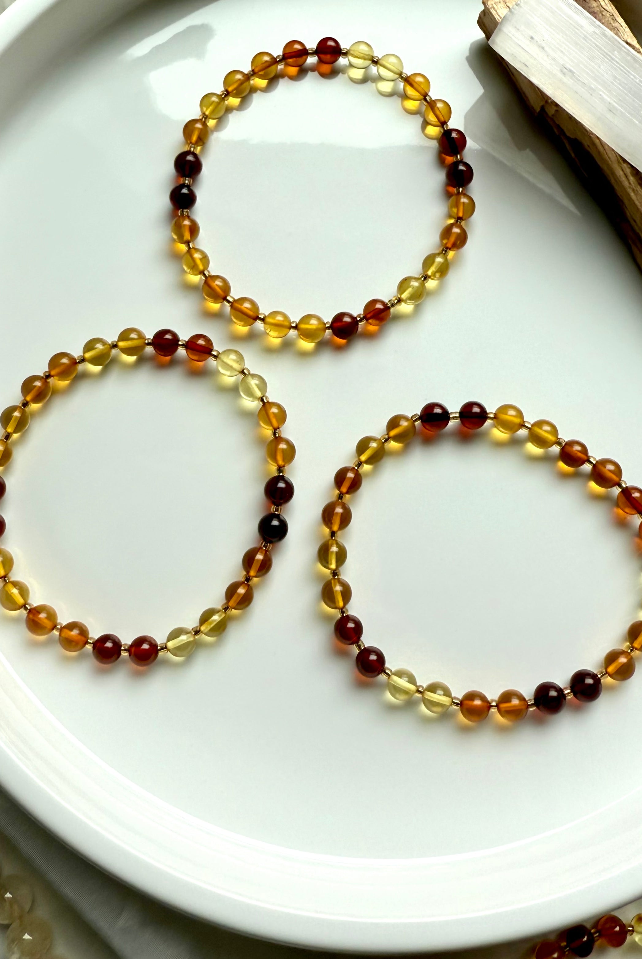 Flat lay of three Baltic amber bracelets in graduated golden tones – solar plexus chakra crystals for vitality + inner strength