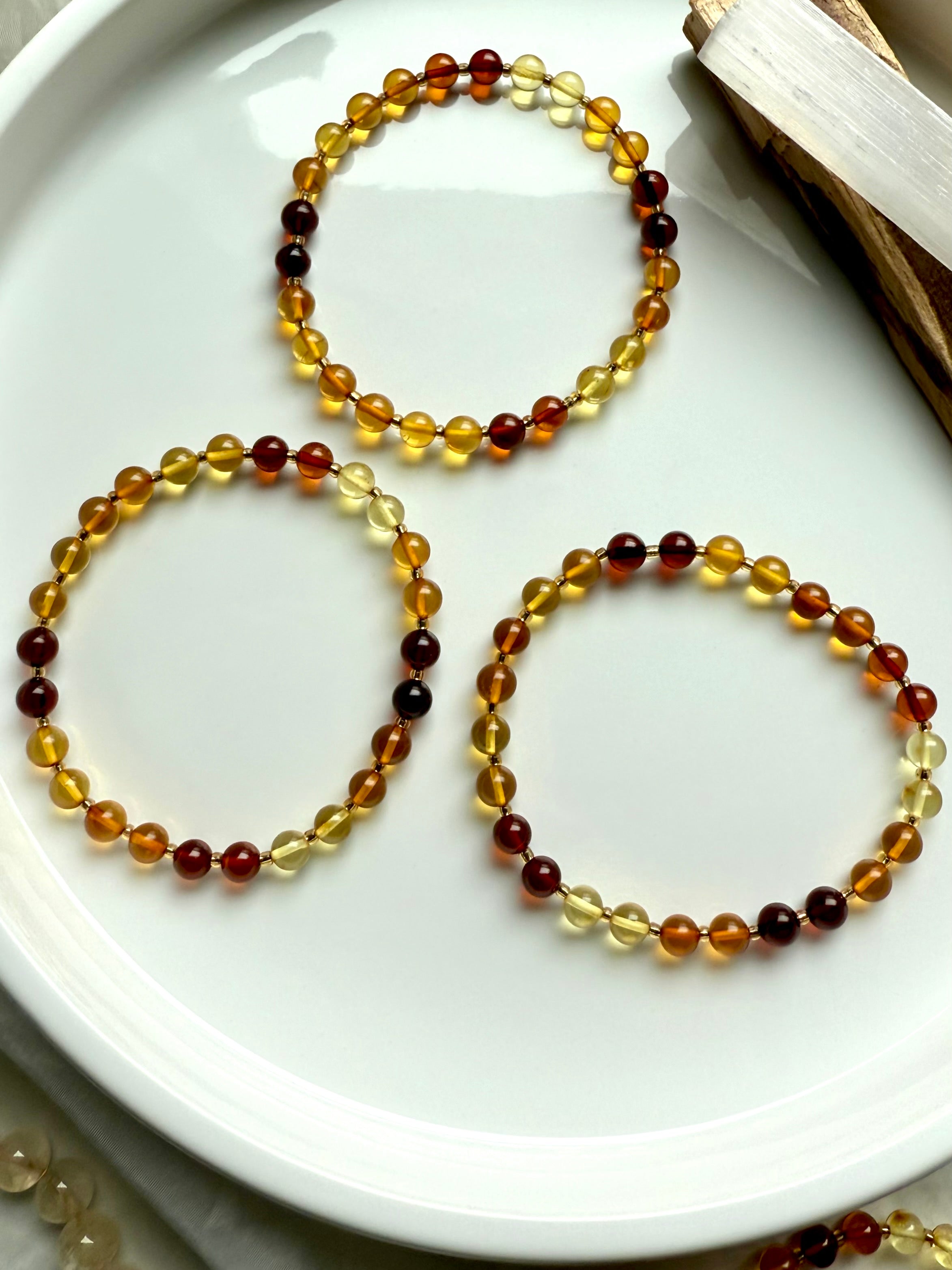 Flat lay of three Baltic amber bracelets in graduated golden tones – solar plexus chakra crystals for vitality + inner strength