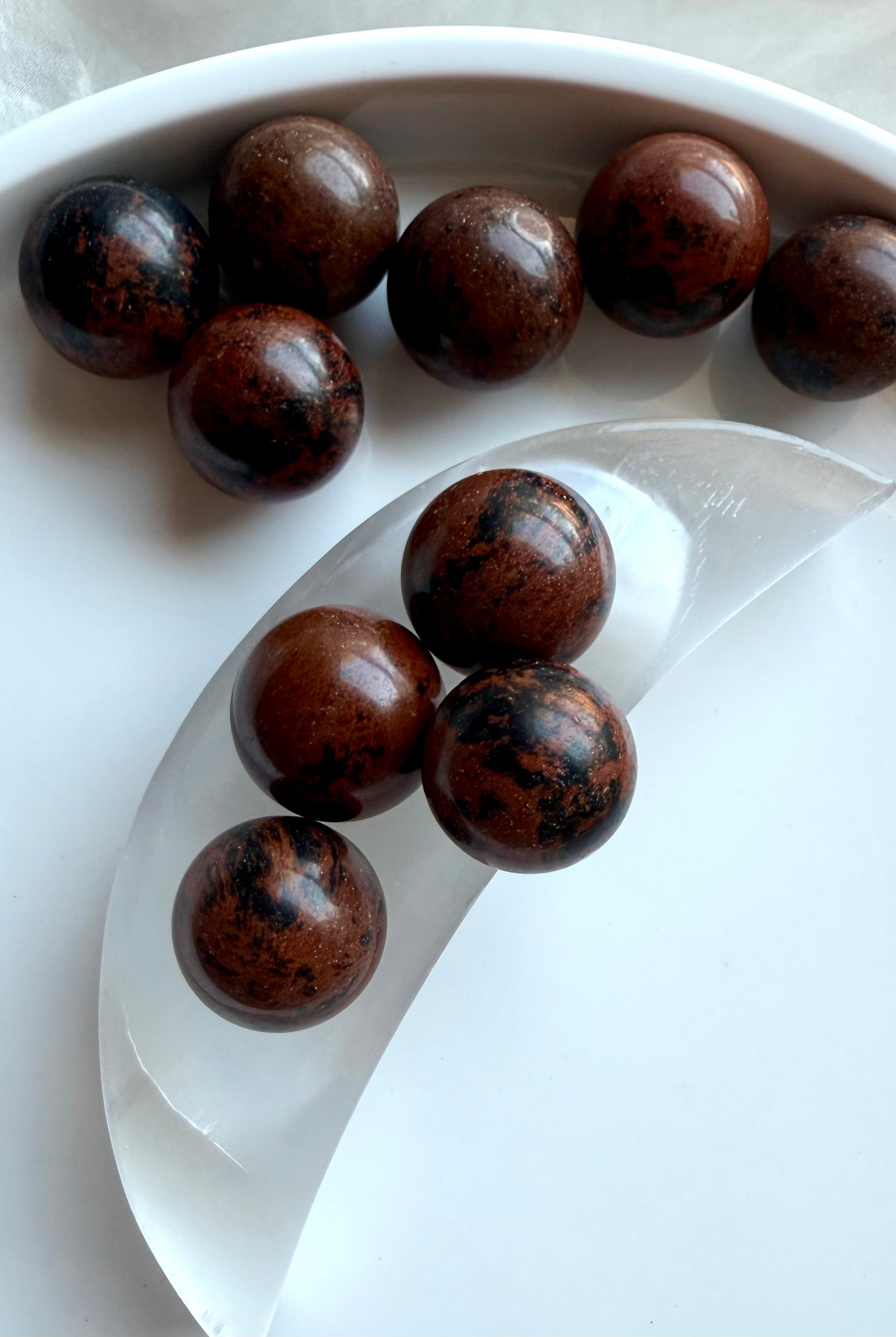 Mahogany Obsidian mini crystal spheres on selenite moon bowl – grounding and protective Root Chakra stones