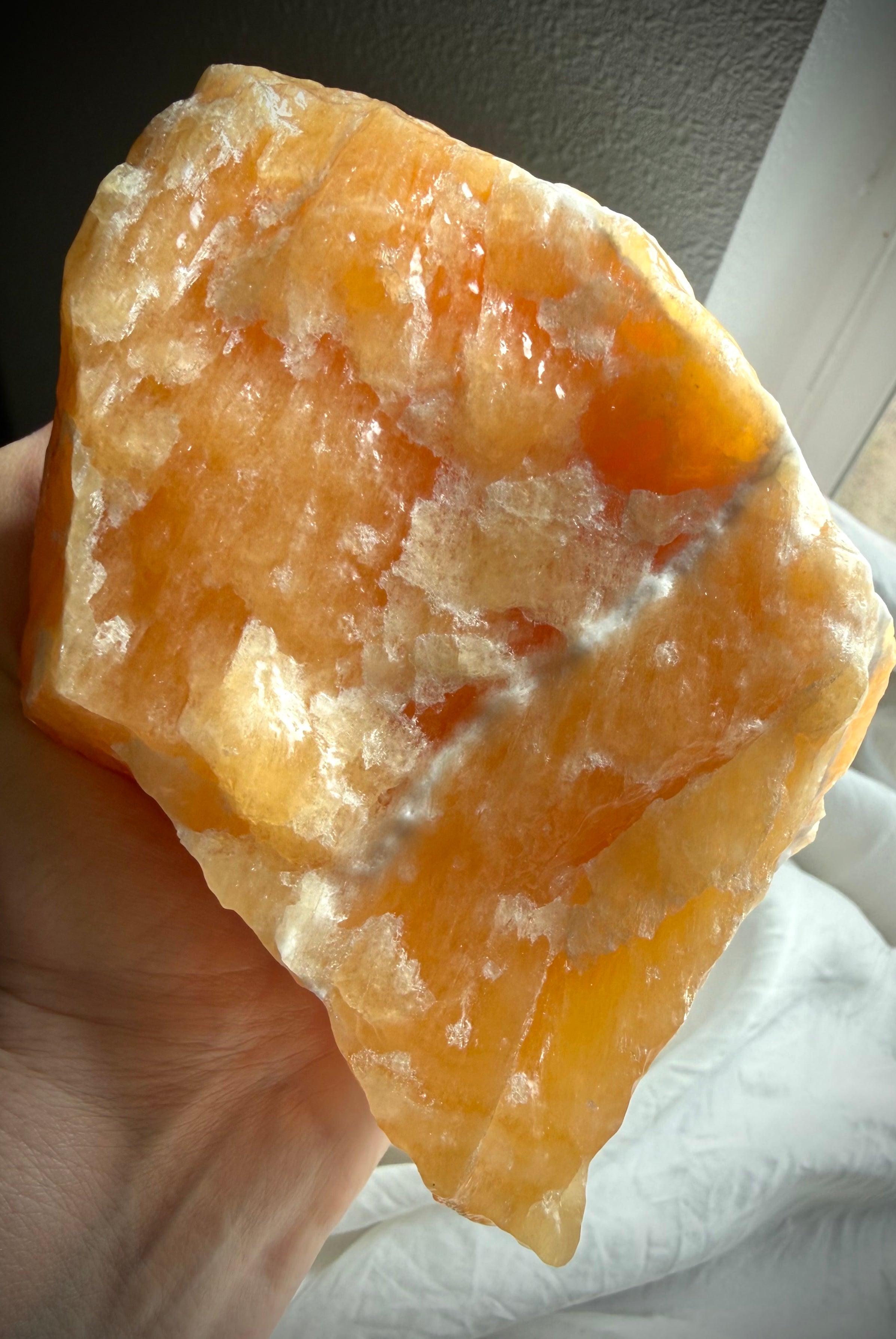 Large Orange Calcite display specimen illuminated by natural light to reveal glowing translucency and depth
