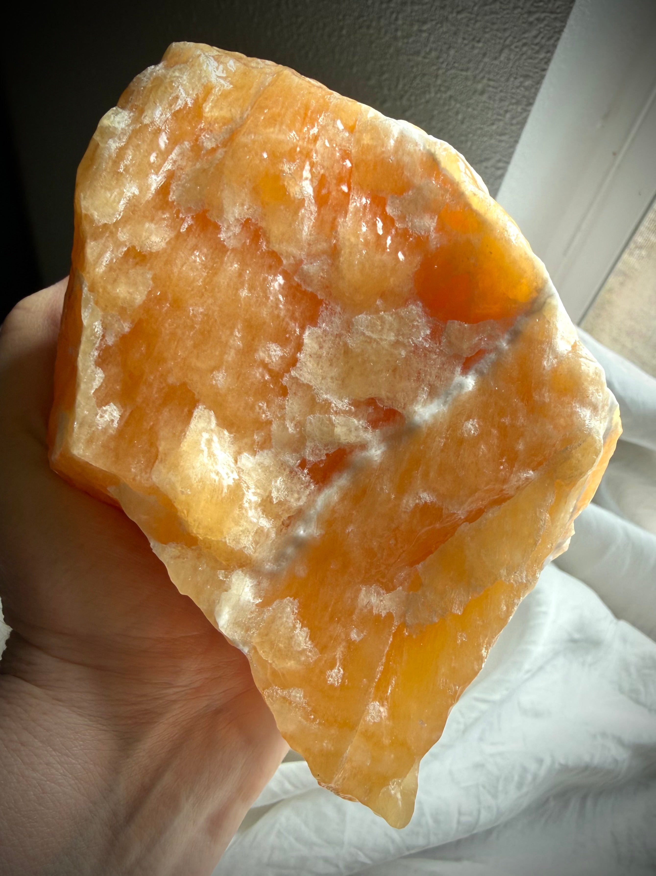 Large Orange Calcite display specimen illuminated by natural light to reveal glowing translucency and depth