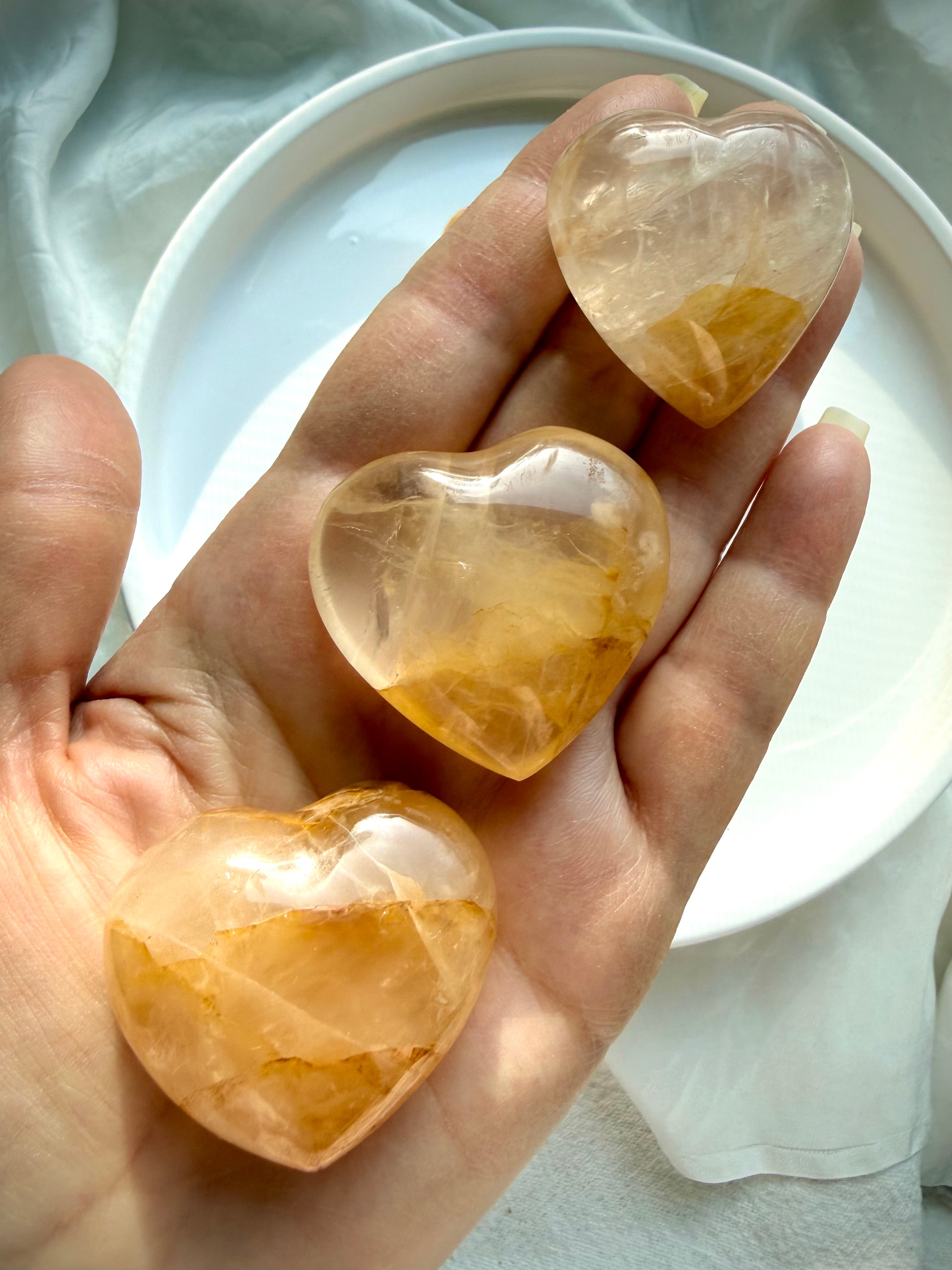 Hand holding one of a kind Golden Healer heart crystals glowing with honey gold tones for empowerment and aligned action