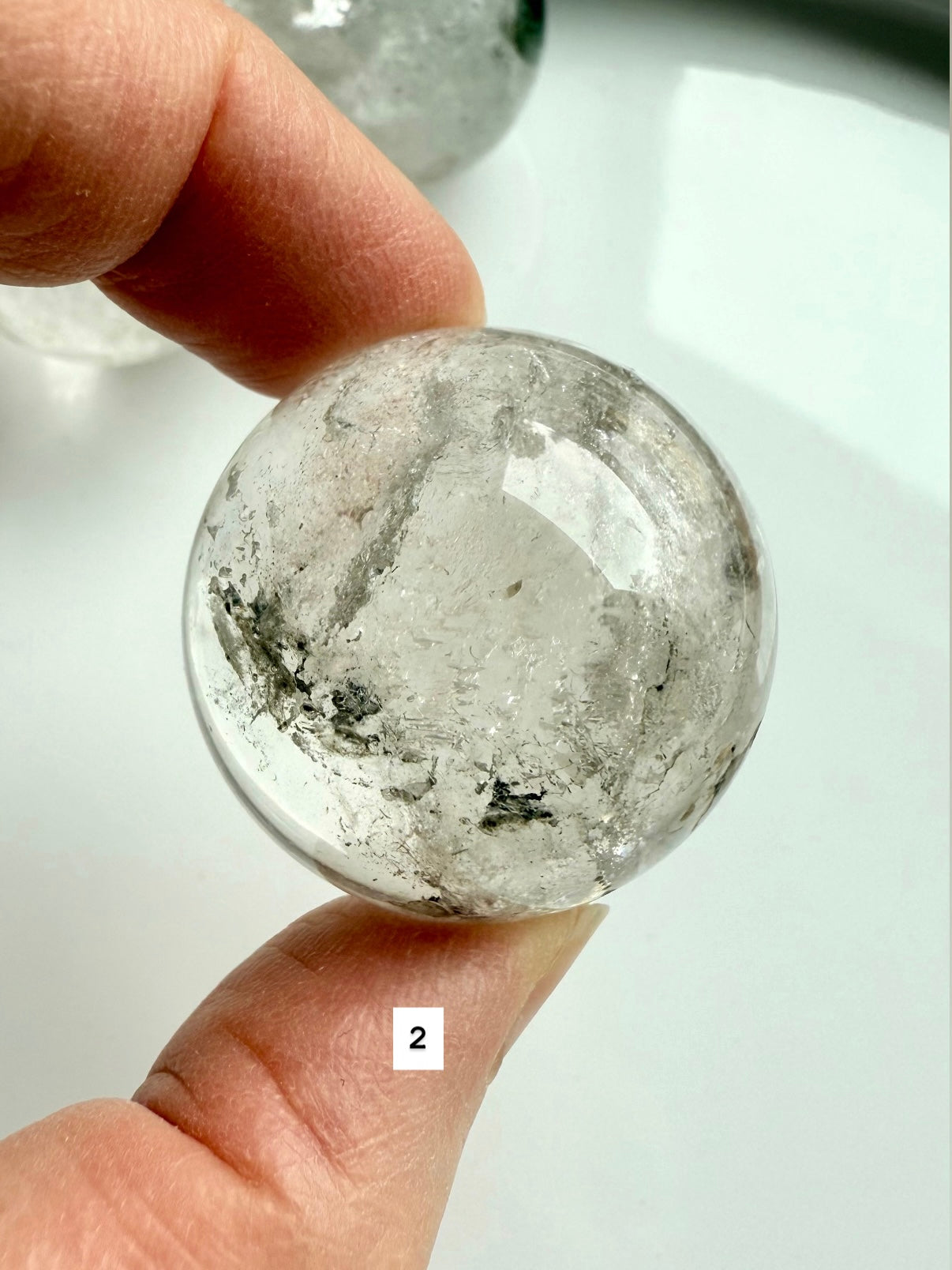 close-up of garden quartz sphere – clear crystal with moss-like inclusions for meditation