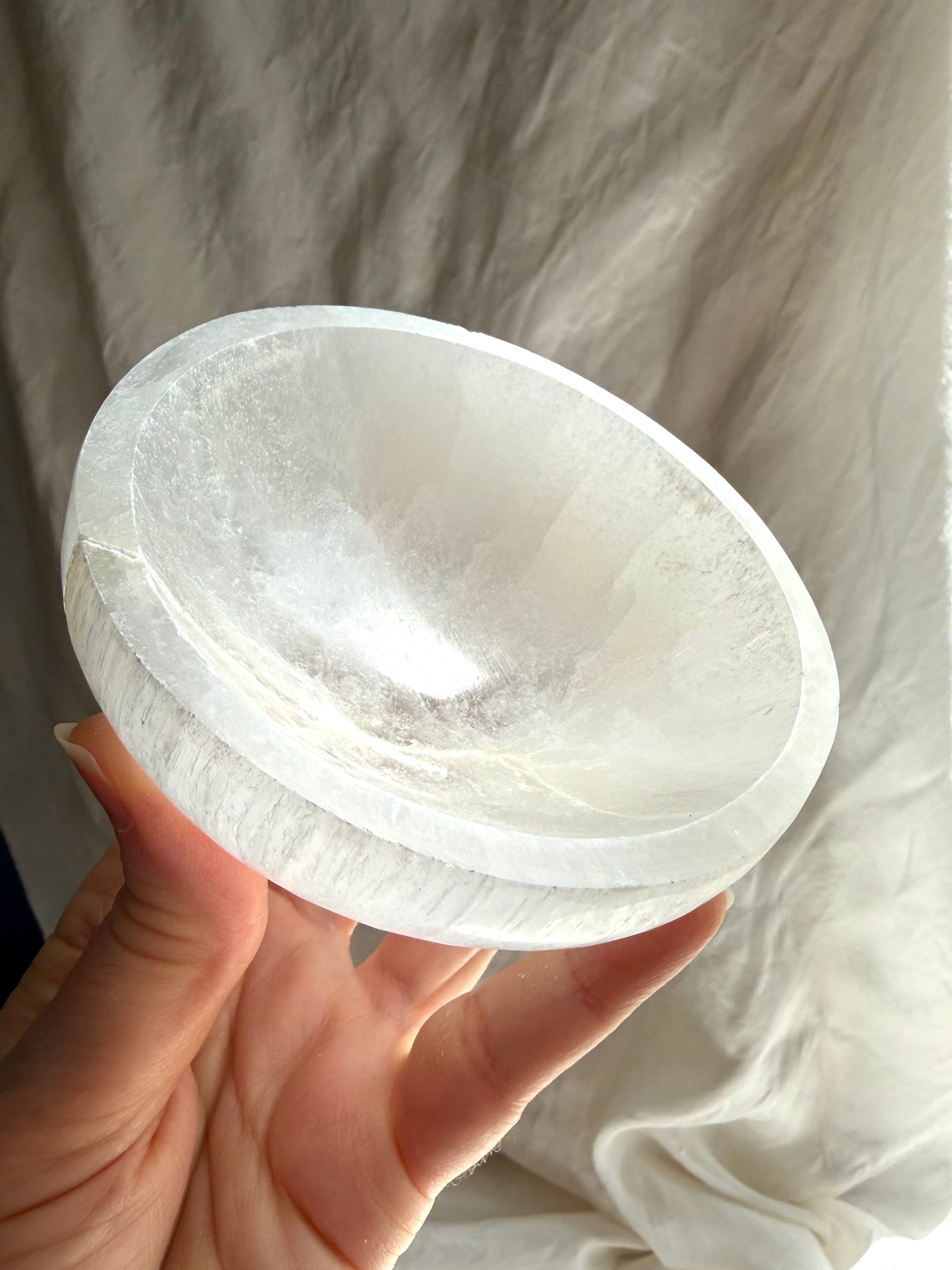 one of a kind selenite charging bowl held in hand, translucent white crystal bowl with natural inclusions for cleansing and altar use
