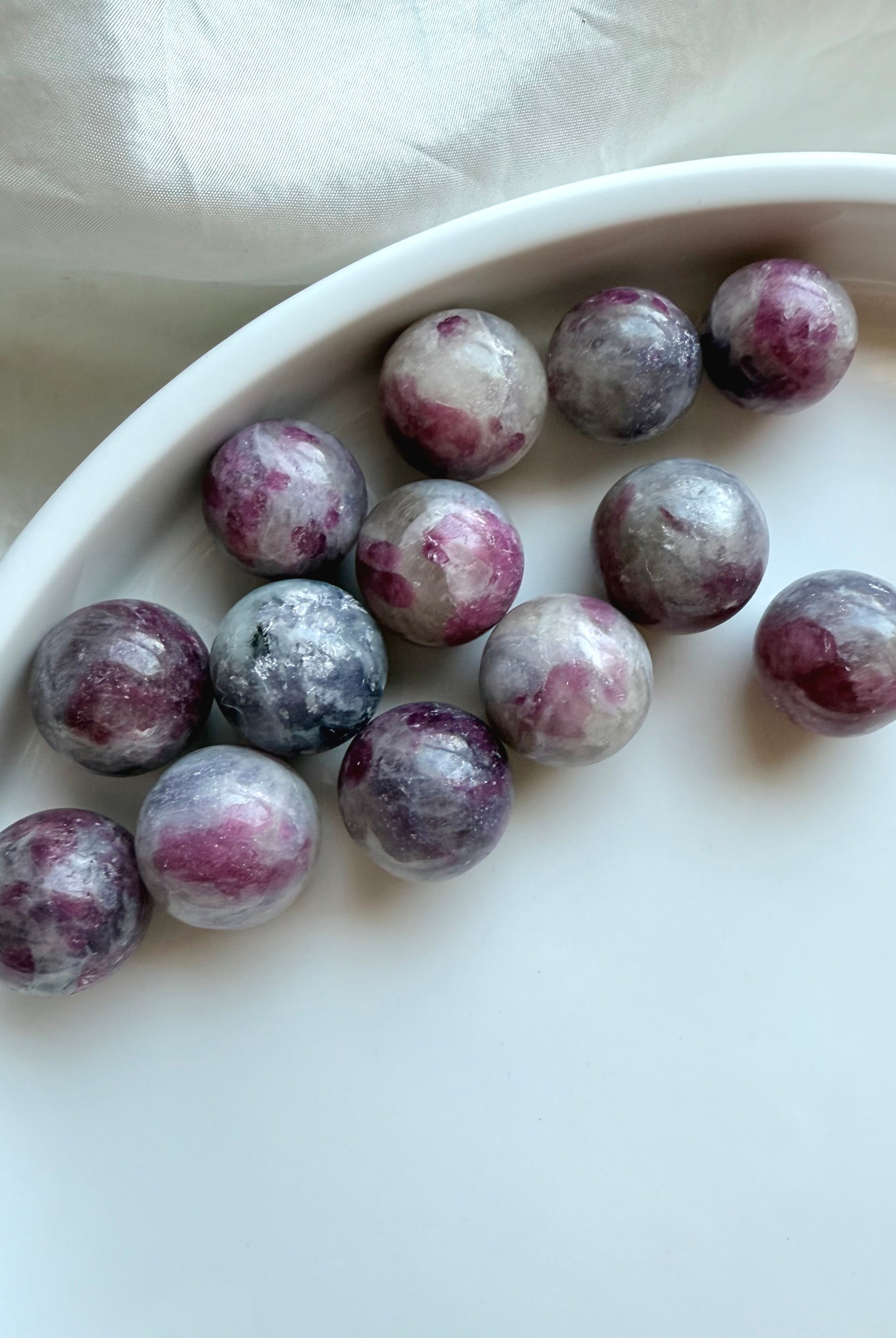 Array of Mini Unicorn Stone spheres with pink tourmaline, lepidolite, and smoky quartz patterns on white dish