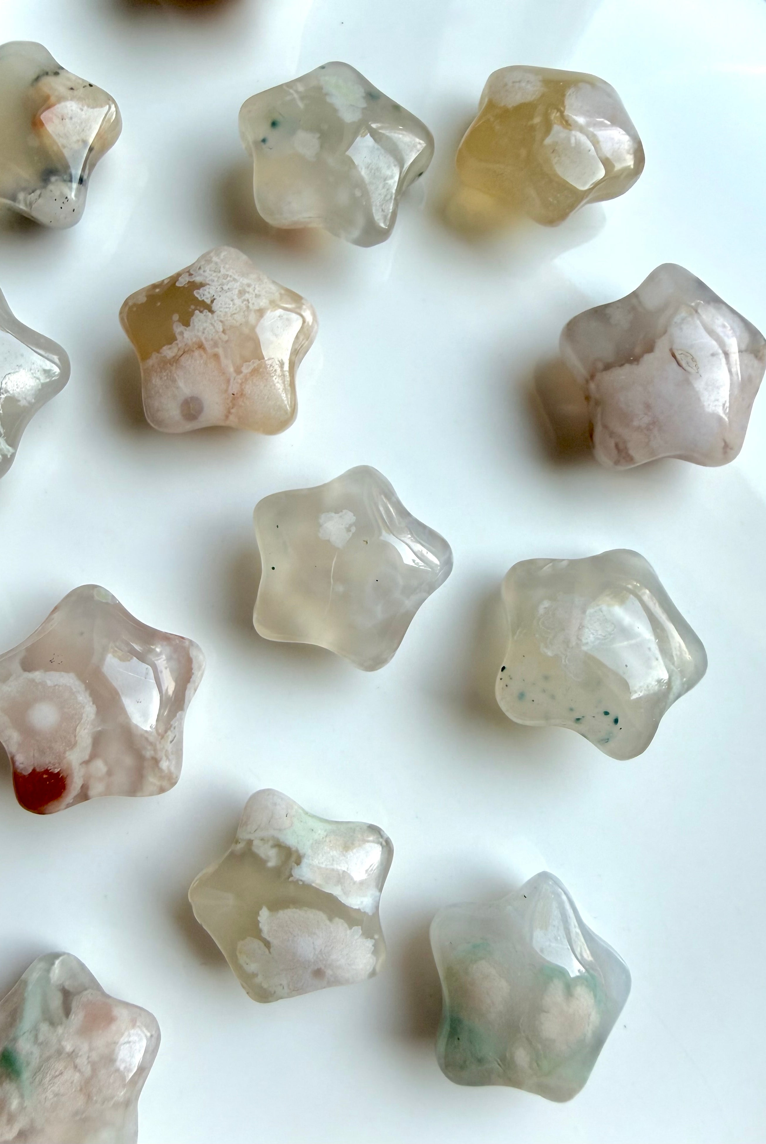 overhead view of mini Flower Agate starfish carvings displaying variation in color, pattern, and floral formations