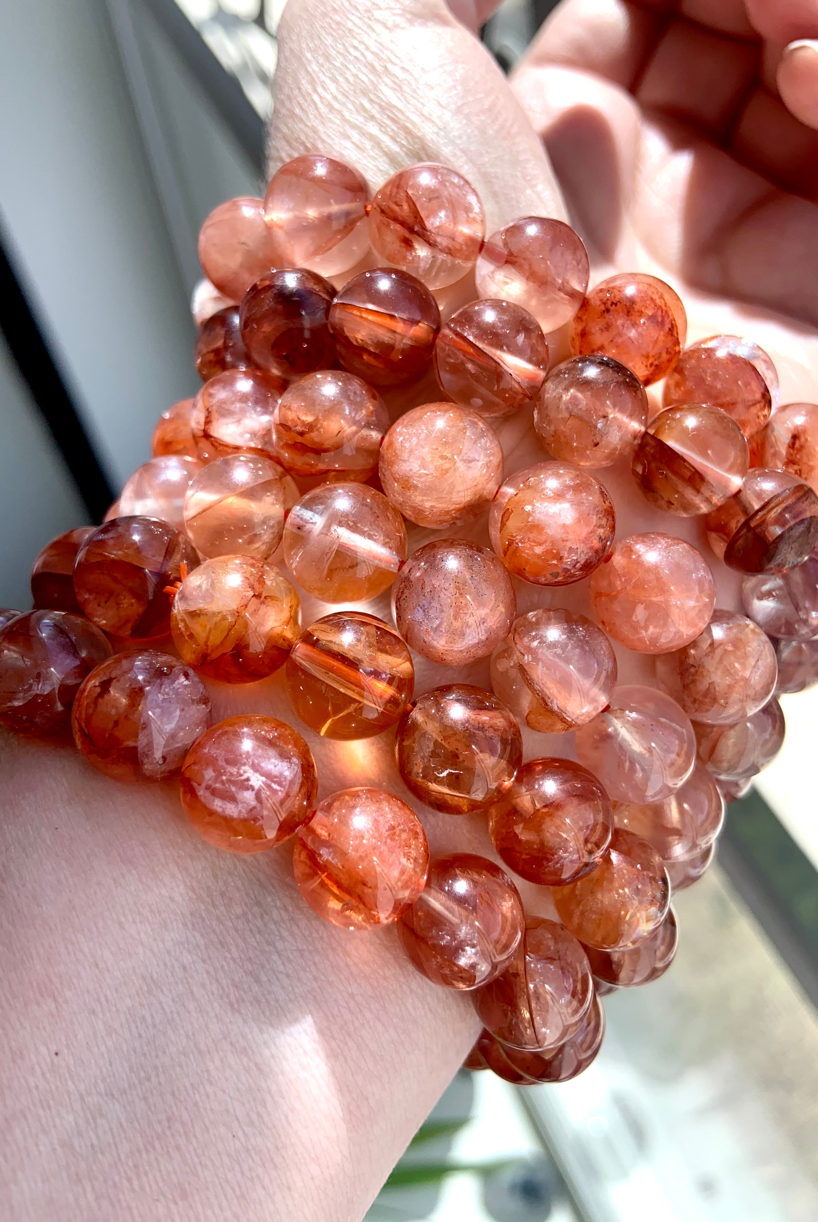 Fire Quartz crystal bracelets worn on wrist, showing vibrant red hematoid quartz beads with excellent clarity and grounding energy