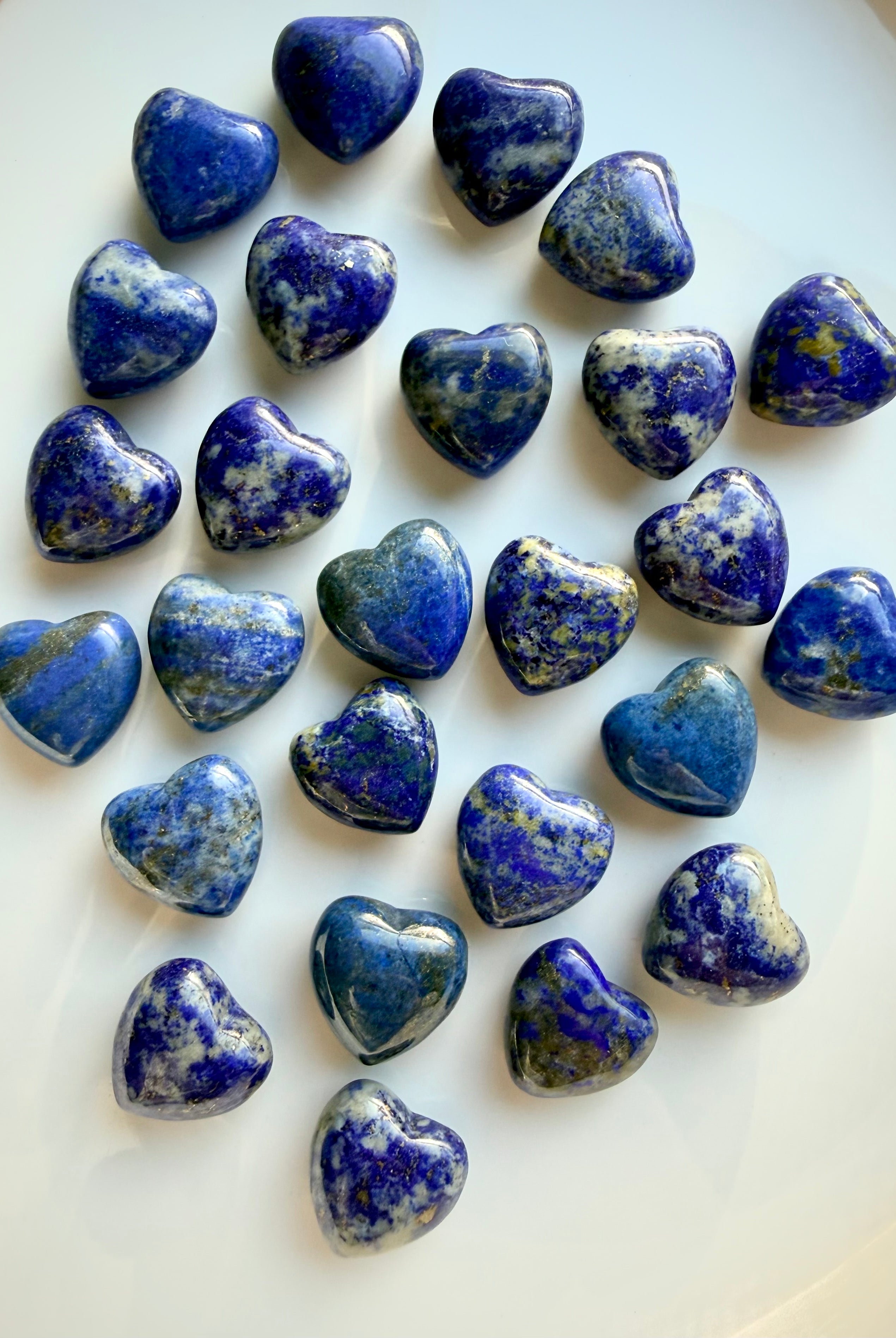 Mini Lapis Lazuli heart carvings showing deep royal blue stone with natural white calcite and gold pyrite inclusions, polished crystal hearts for wisdom and truth